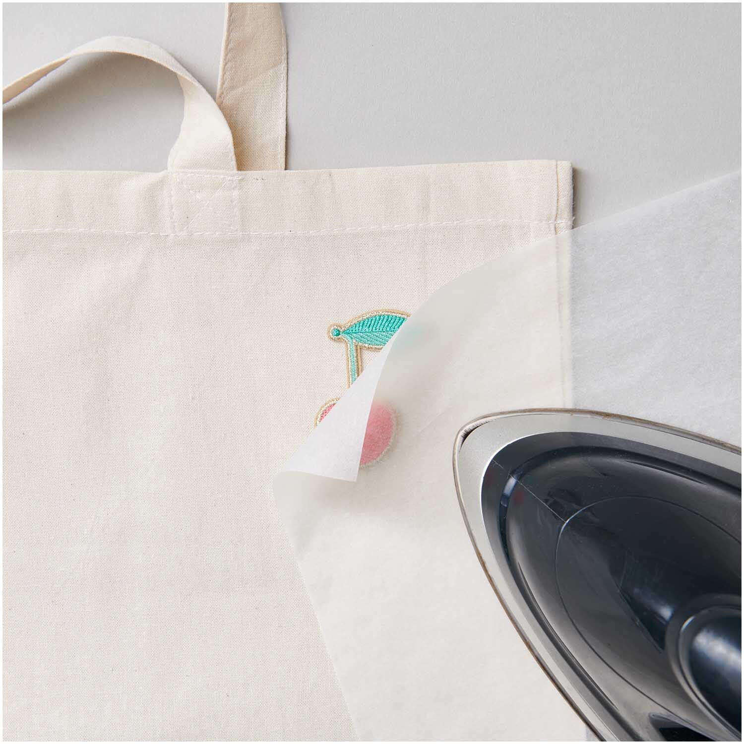 Patch Kirsche zum Aufbügeln 4x5,3cm von Rico Design auf einer Tasche mit Bügeleisen. Ideal für kreative Textilveredelung.