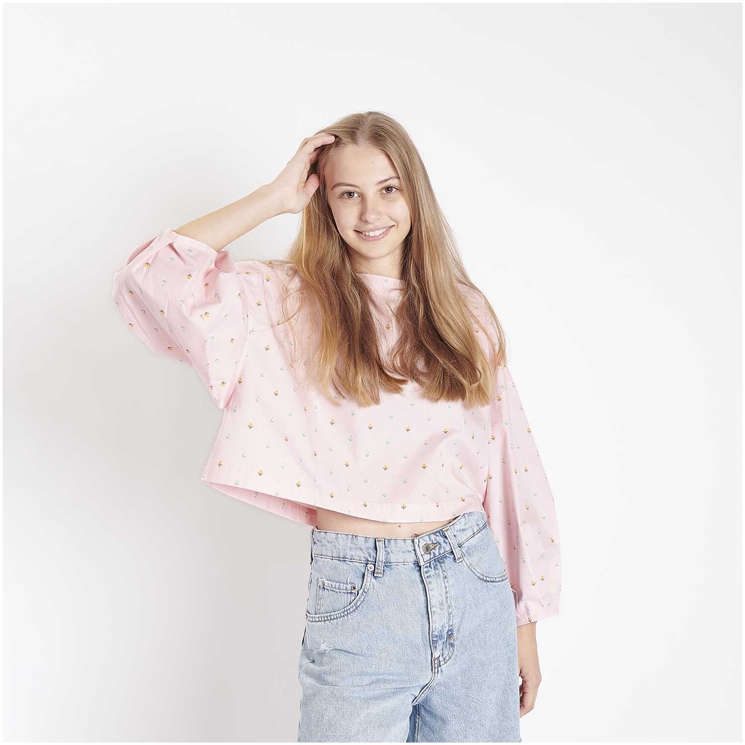Stoffabschnitt Baumwoll-Popelin Pixel Blumen Rosa: Frau trägt rosa Oberteil mit Blumenmuster von Rico Design, kombiniert mit Jeans.