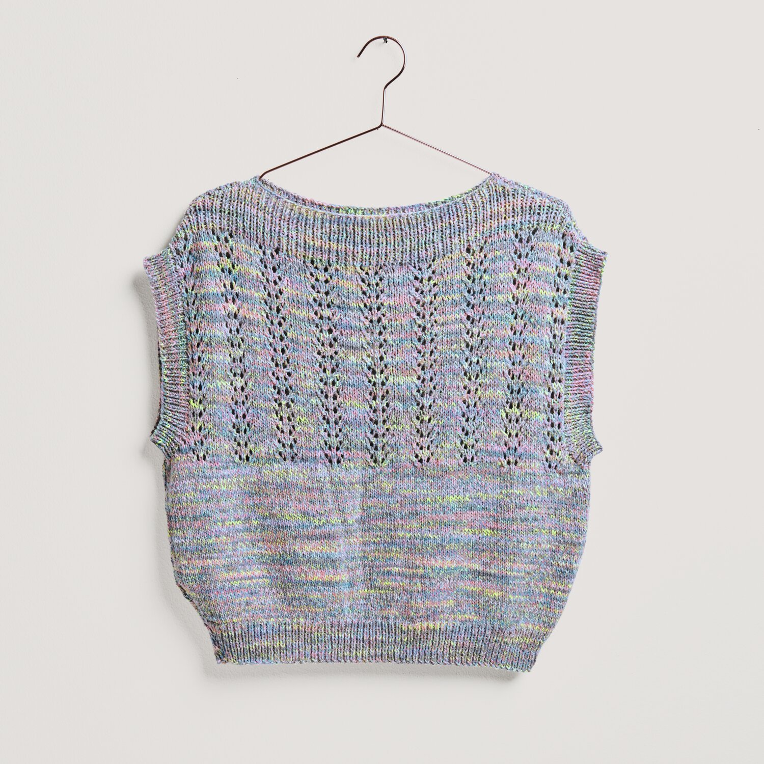 Strickset Top Modell 20 aus Lovewool No. 20, pastellfarben, mit Ethno-Muster, auf einem Bügel.
