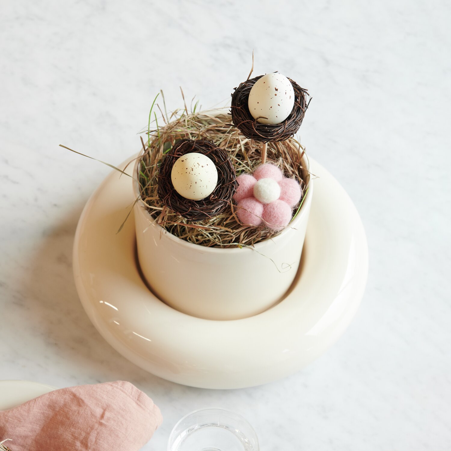 Stecker Ei im Nest: Dekoratives Arrangement mit Filz-Blumen in Naturtönen auf weißem Untergrund.