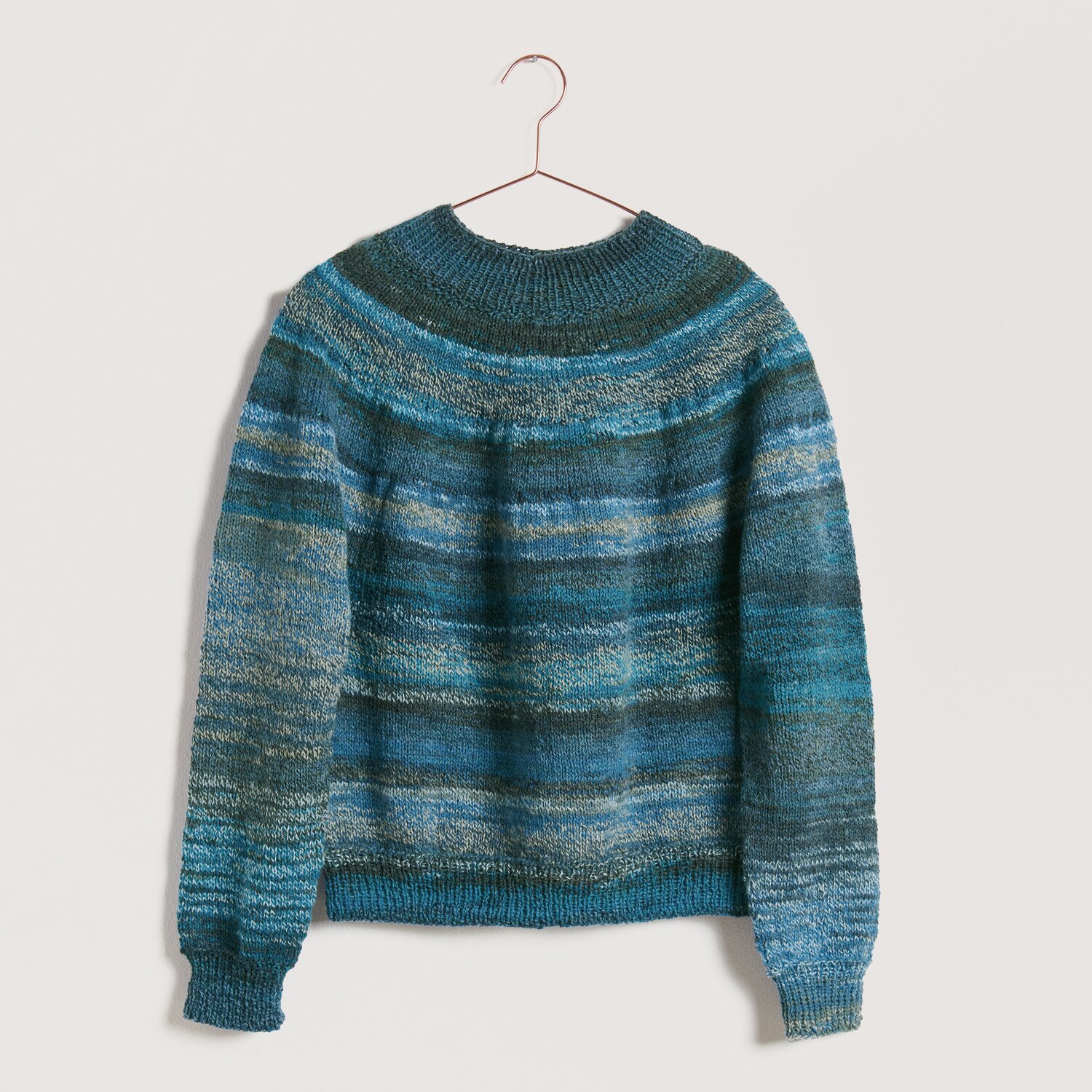 Strickset Pullover Modell 24 aus Die Neue Masche No. 10, blau-grün gestreift, auf einem Kleiderbügel vor neutralem Hintergrund.