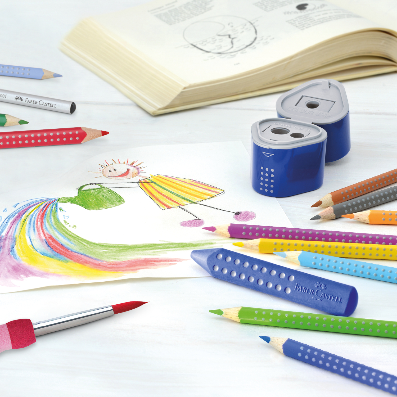 Colour Grip 2001 Buntstifte und Anspitzer von Faber Castell auf einem Tisch mit Kinderzeichnung.