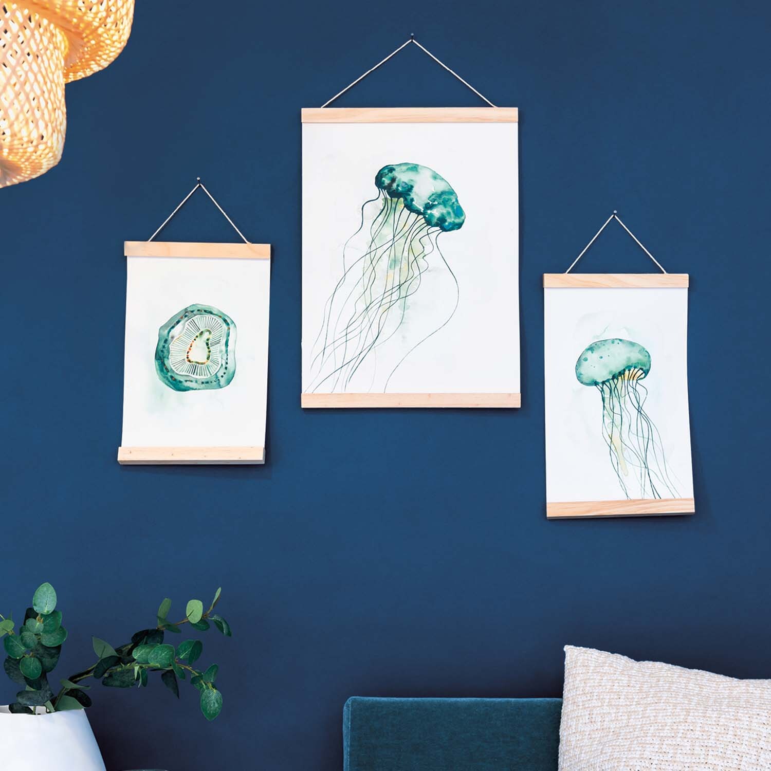 Anleitung Quallen aquarellieren: Drei gerahmte Aquarelle von Quallen an einer blauen Wand.