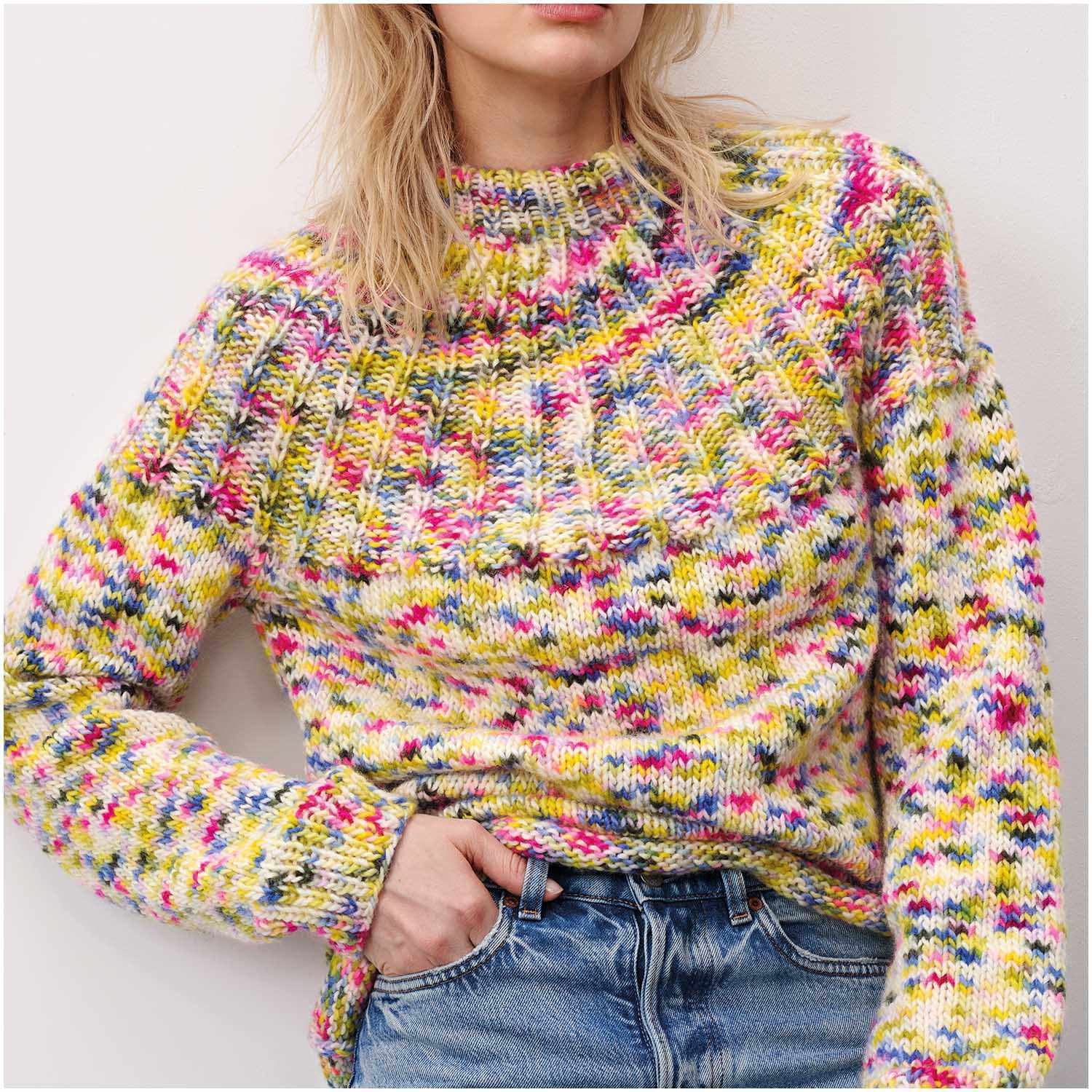 Luxury Hand-Dyed Happiness chunky: Frau trägt gestrickten Pullover in Pink-Gelb von Rico Design, lässig kombiniert mit Jeans.
