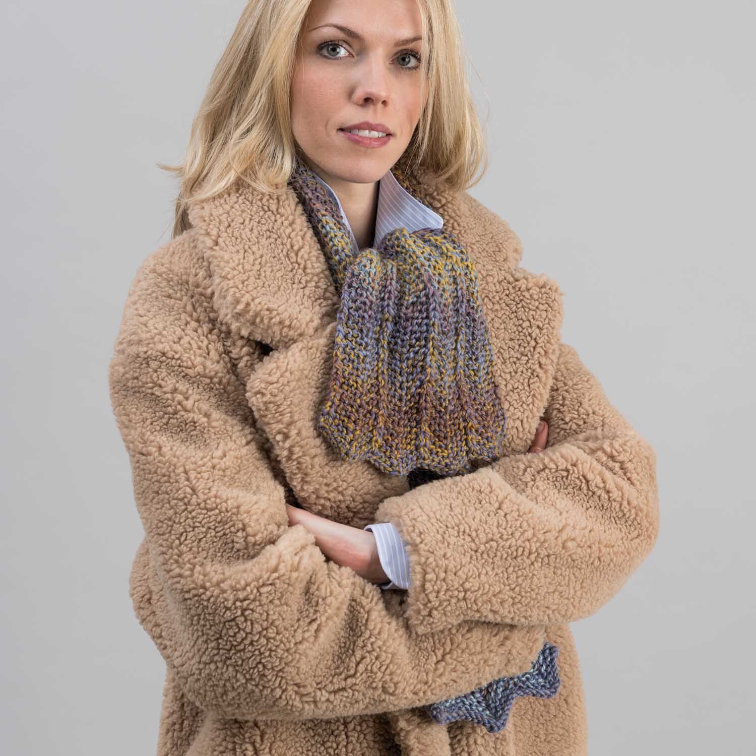 Strickanleitung Schal aus Creative Ito Iro chunky: Frau trägt bunten Schal und beigen Mantel.