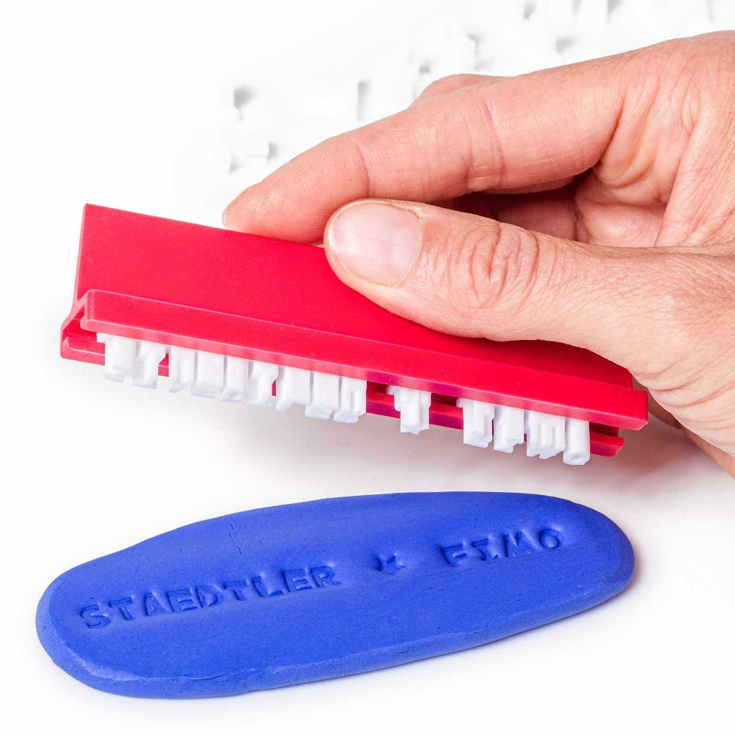 FIMO Zubehör Stempelset: Hand hält roten Stempel über blauer Tonplatte mit Staedtler-Prägung.