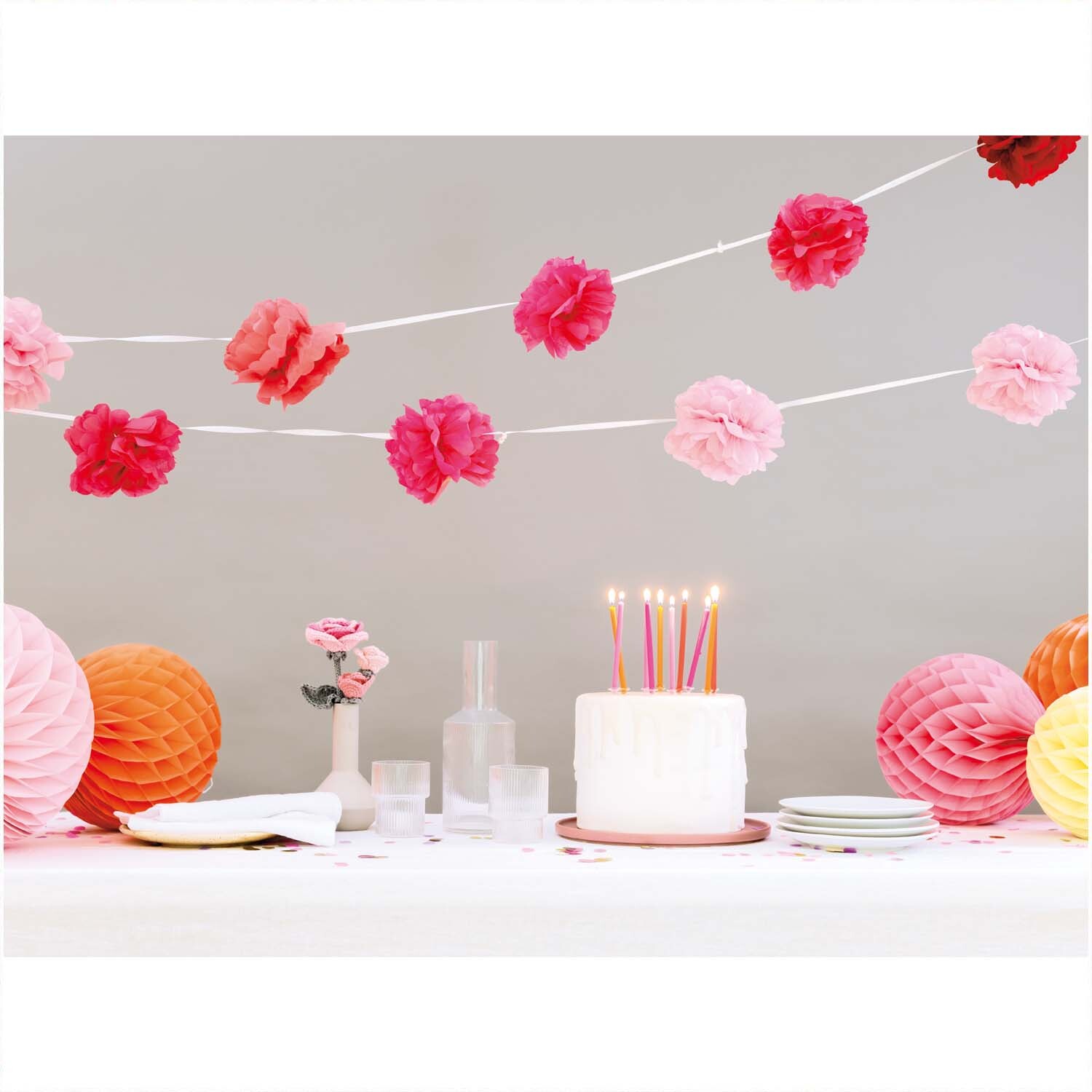 Pompon-Girlande pink 180cm 2 Stück von Rico Design schmückt einen festlichen Tisch mit Kerzen und Dekorationen in Rosa- und Orangetönen.