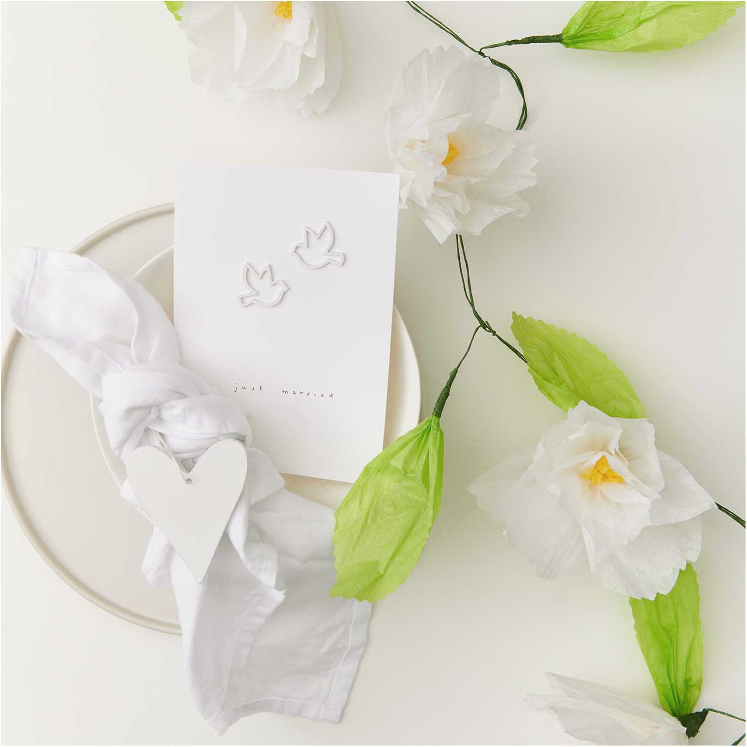 Papierblumen Girlande weiß 180 cm: Elegante Deko mit weißen Blüten und grünen Blättern.