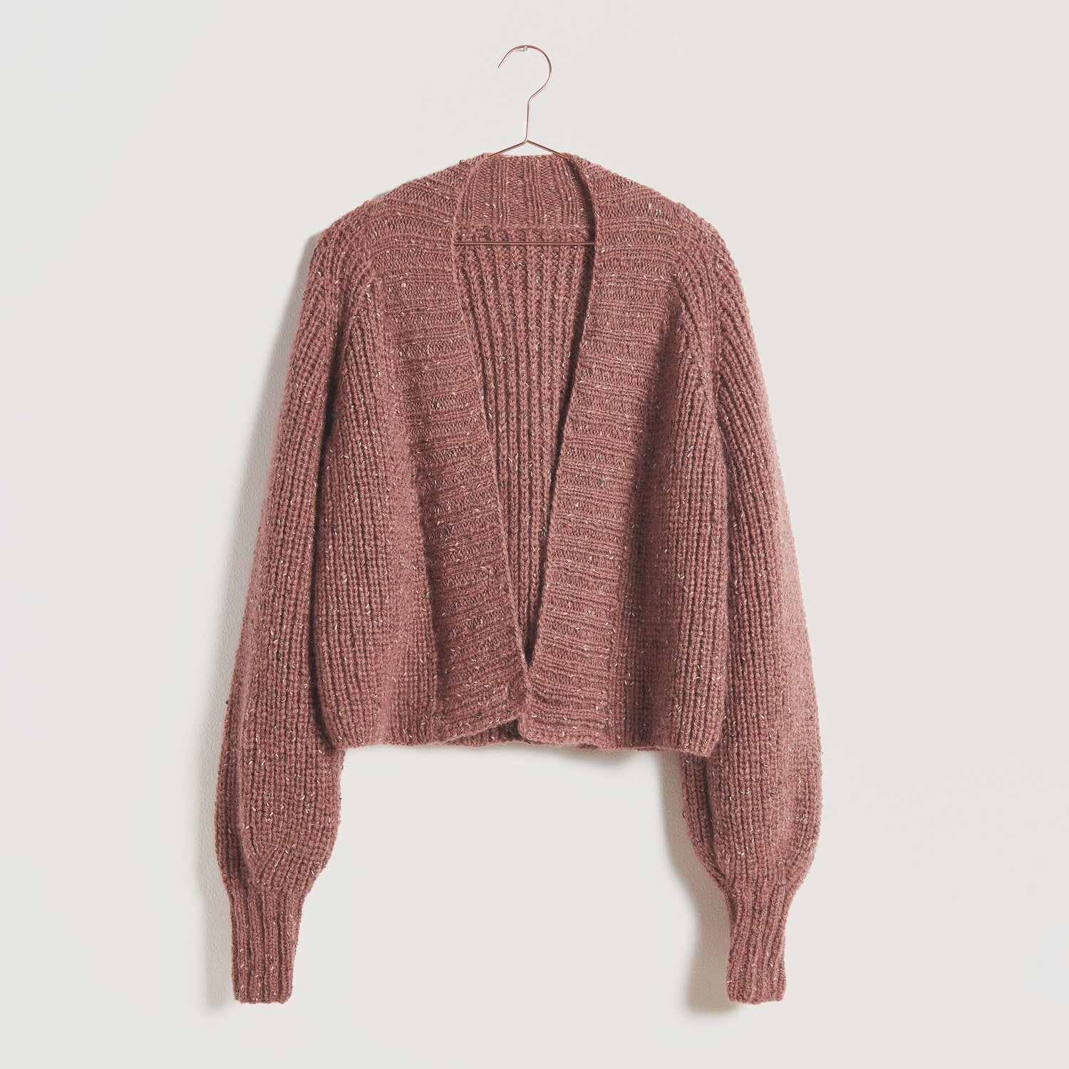 Strickset Jacke Modell 17: Eine grob gestrickte, langärmelige Jacke in warmem Braunton auf einem Kleiderbügel.