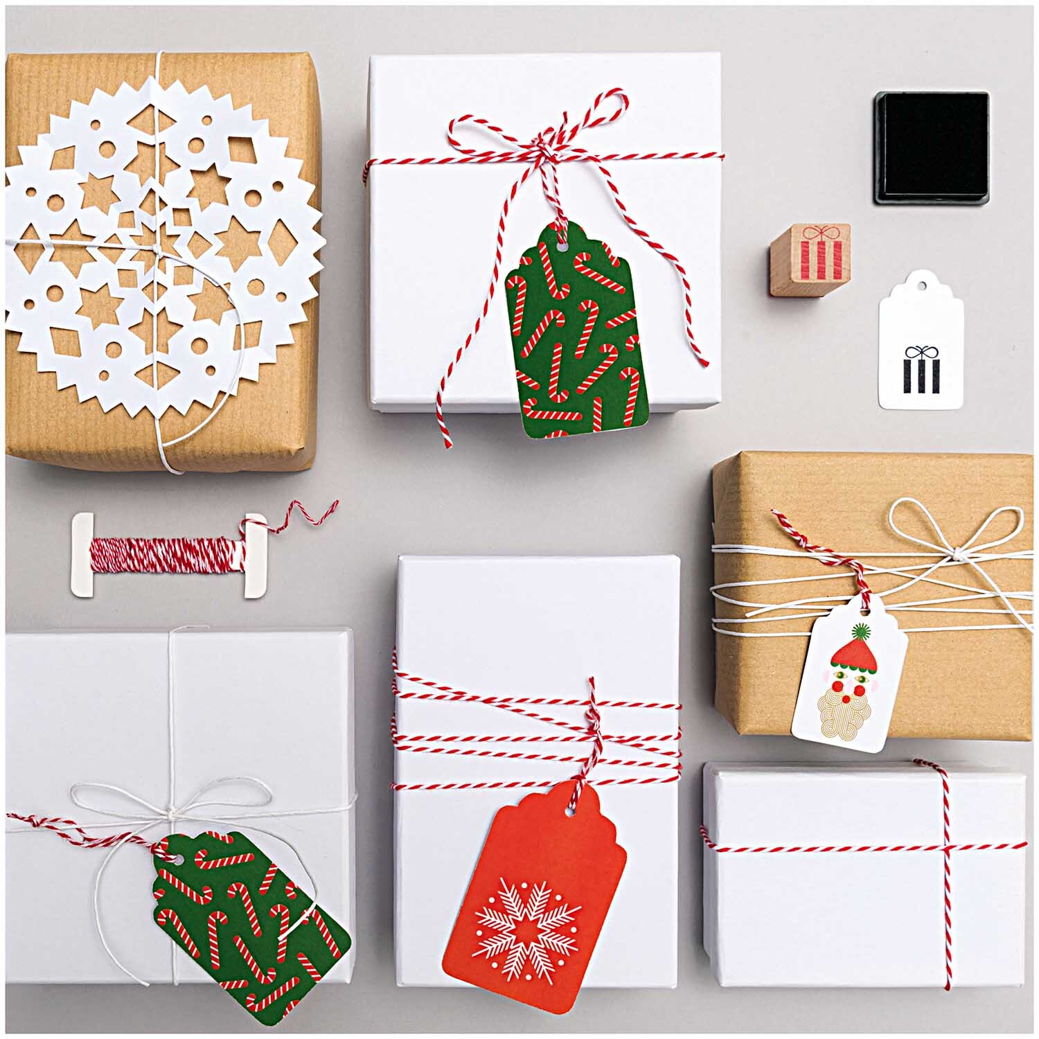 Paper Poetry Packpapier umwickelt Geschenke mit roten und weißen Bändern, dekoriert mit festlichen Anhängern.