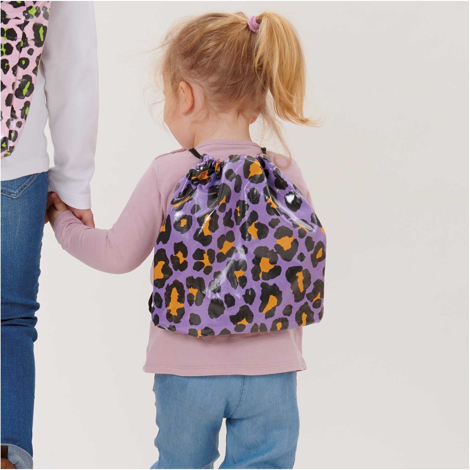Stoffabschnitt PVC-Stoff Glossy Acid Leo lila 25x70cm: Kind mit lila Leopardenmuster-Rucksack von Rico Design.