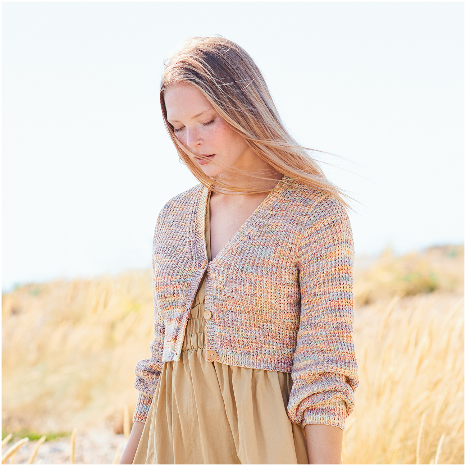 Creative Summer Sprinkles: Frau trägt pastellfarbenen Cardigan von Rico Design in sommerlicher Landschaft.