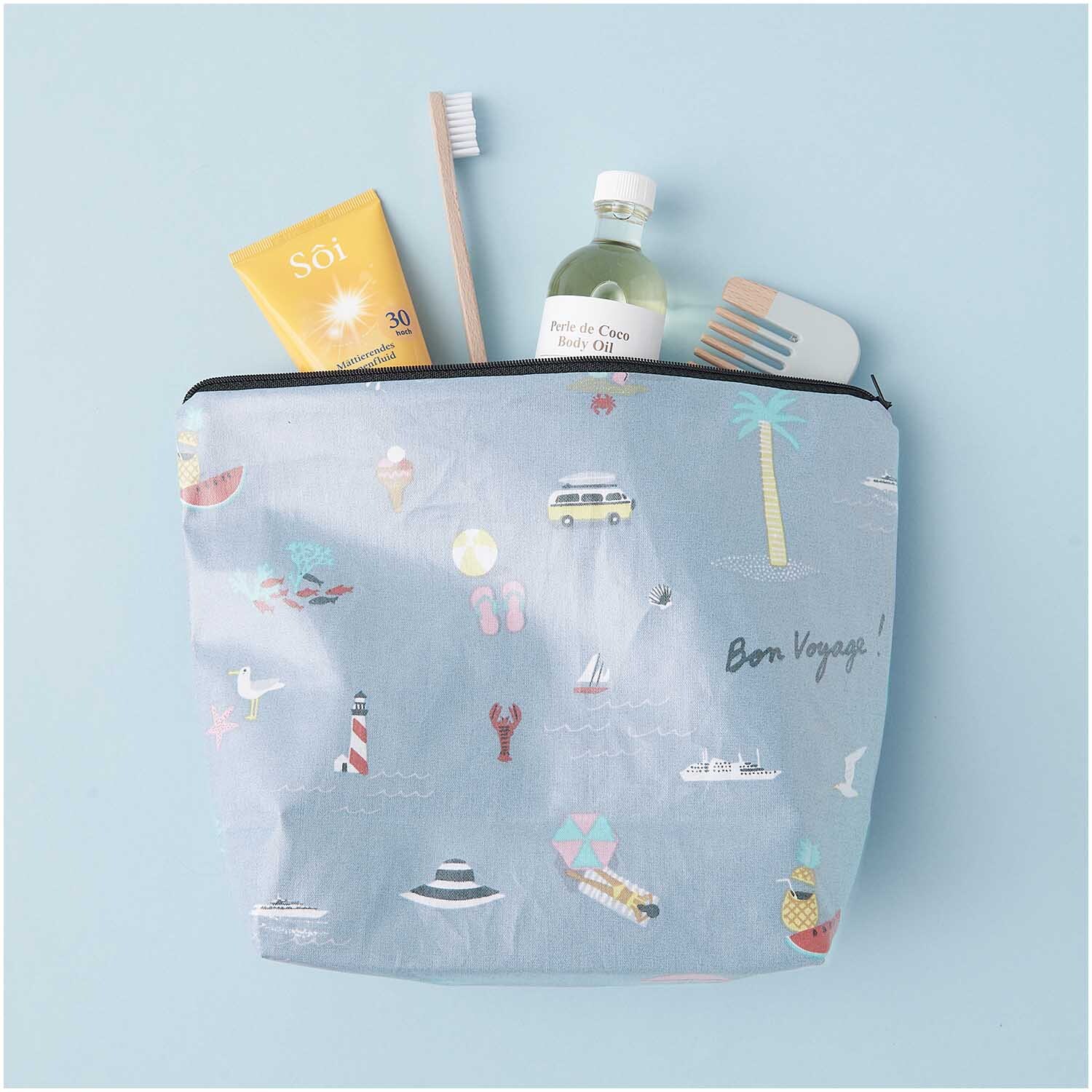 Kosmetiktasche Travel the World mit blauem Design, gefüllt mit Zahnbürste, Sonnencreme und Öl.
