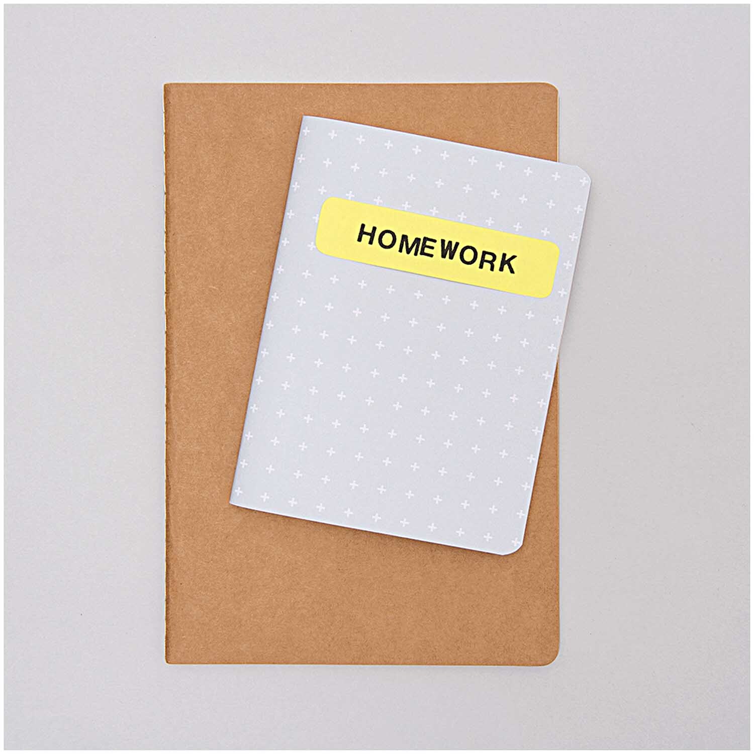 Paper Poetry Notizbuch A5 Kraftpapier blanko von Rico Design, mit einem kleineren Notizbuch mit "HOMEWORK"-Aufschrift auf grauem Hintergrund.