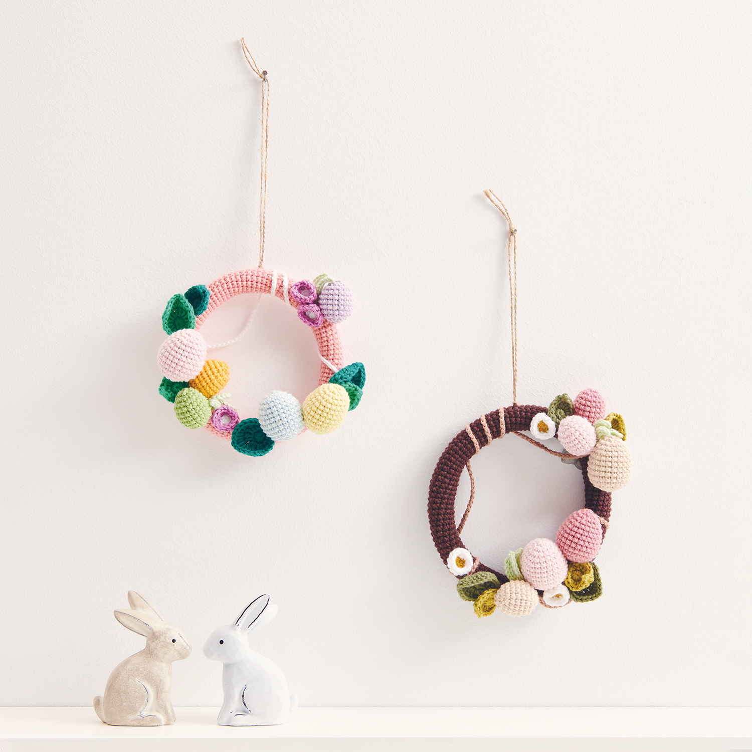 Häkelanleitung Ricorumi Osterkranz: Zwei bunte, gehäkelte Kränze mit Blumen und Hasenfiguren auf weißem Hintergrund.