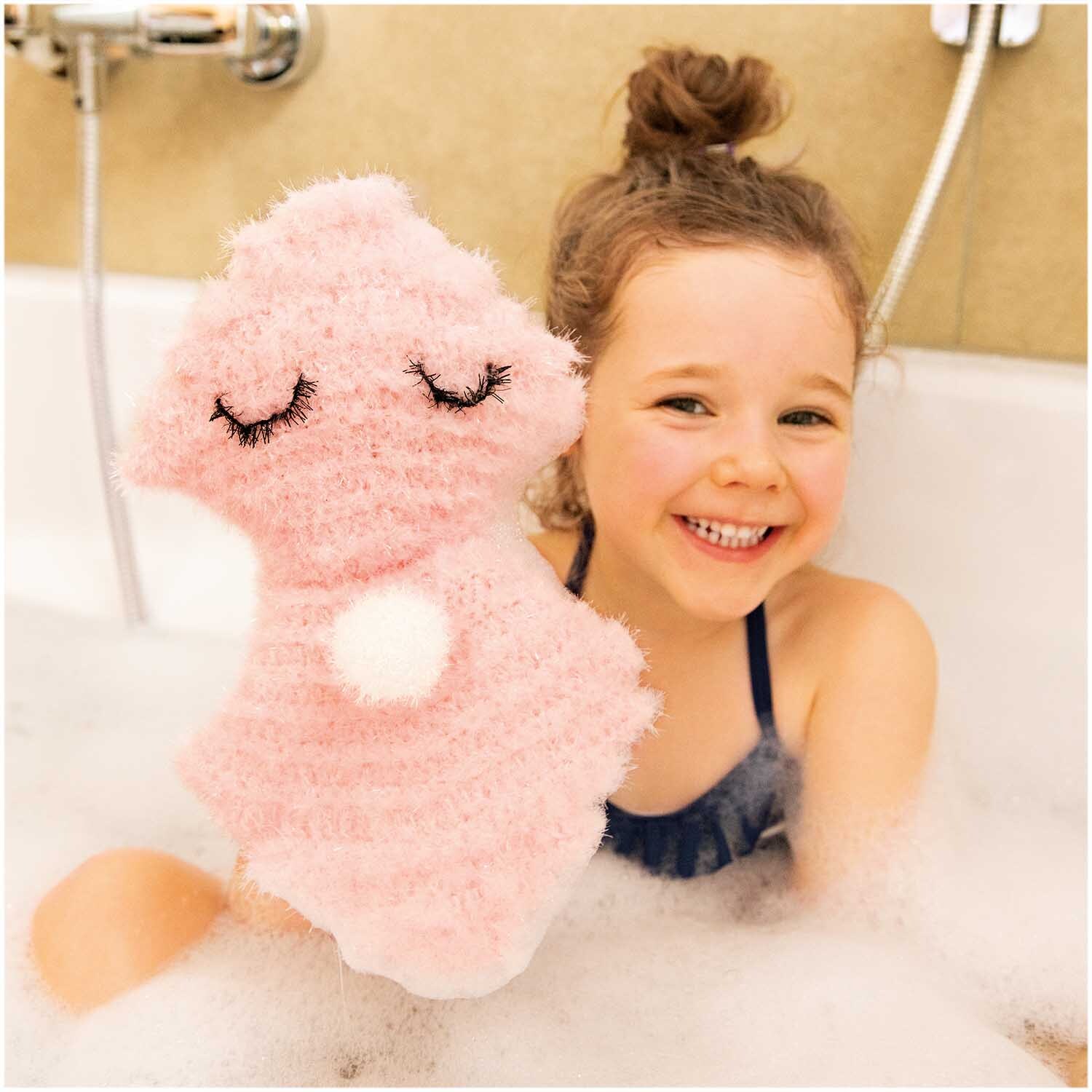 Creative Bubble: Ein lachendes Kind in der Badewanne hält einen rosa, flauschigen Waschlappen von Rico Design.