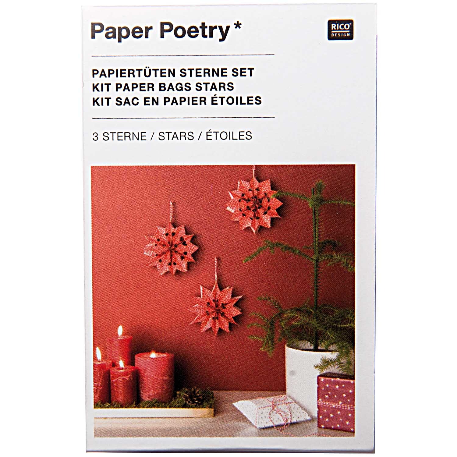 Paper Poetry Bastelset Papiertüten-Sterne Punkte klein zeigt rote Sterne aus Papier, dekoriert mit Kerzen und einem kleinen Tannenbaum.