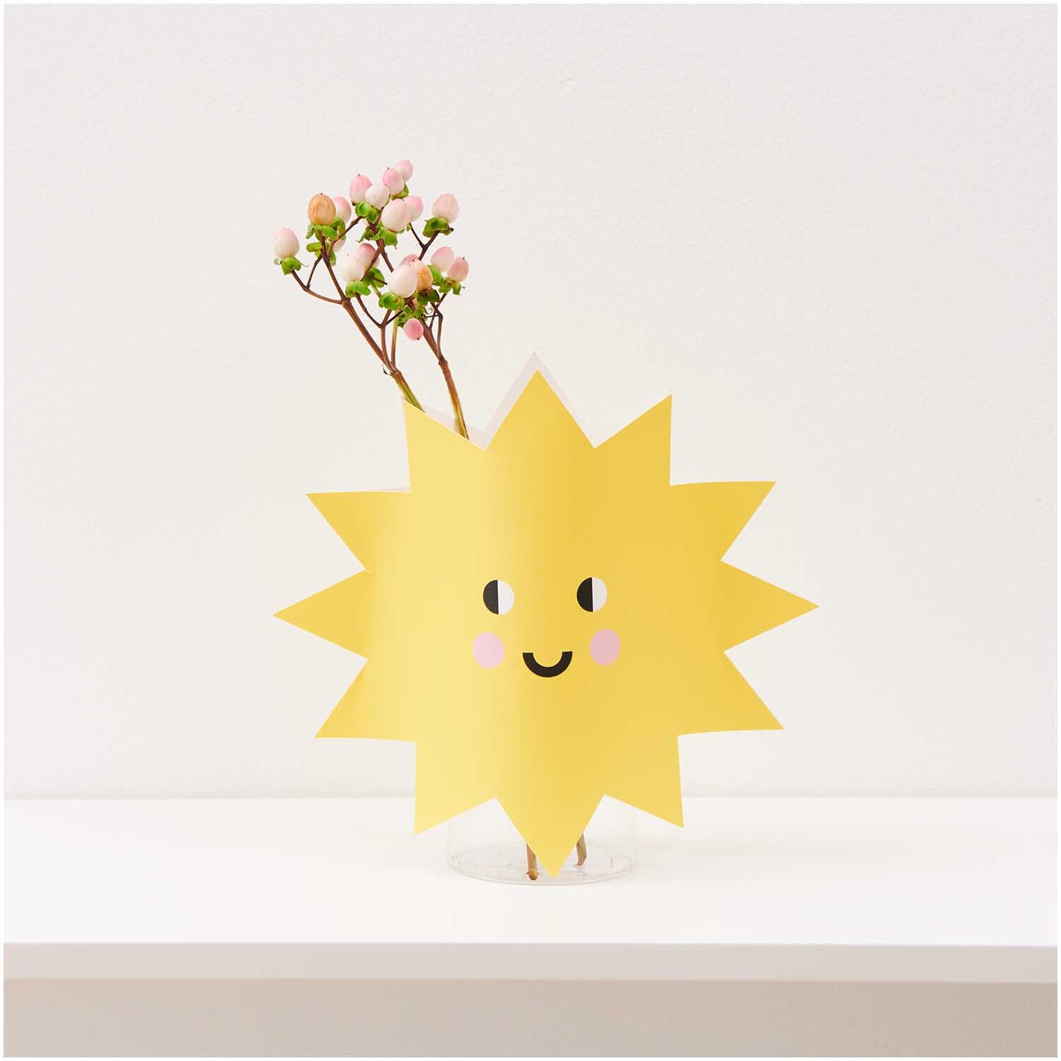 Paper Poetry Vasencover Sonne in Gelb mit lächelndem Gesicht, dekoriert mit rosa Blütenzweigen.
