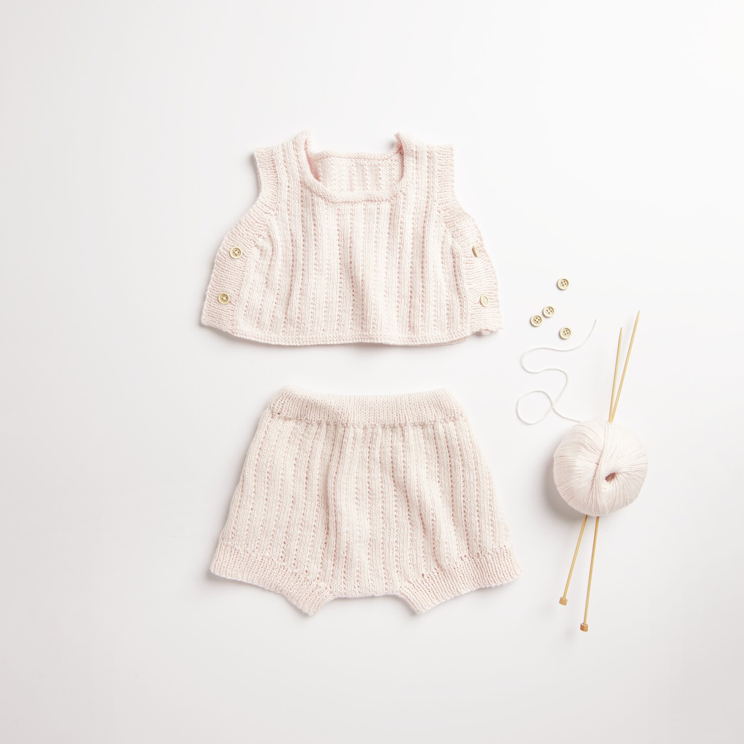 Baby Cozy Organic Cotton Cashmere: Strickset in Rosa mit Oberteil und Shorts, Wolle und Stricknadeln. Ideal für zarte Babyhaut.