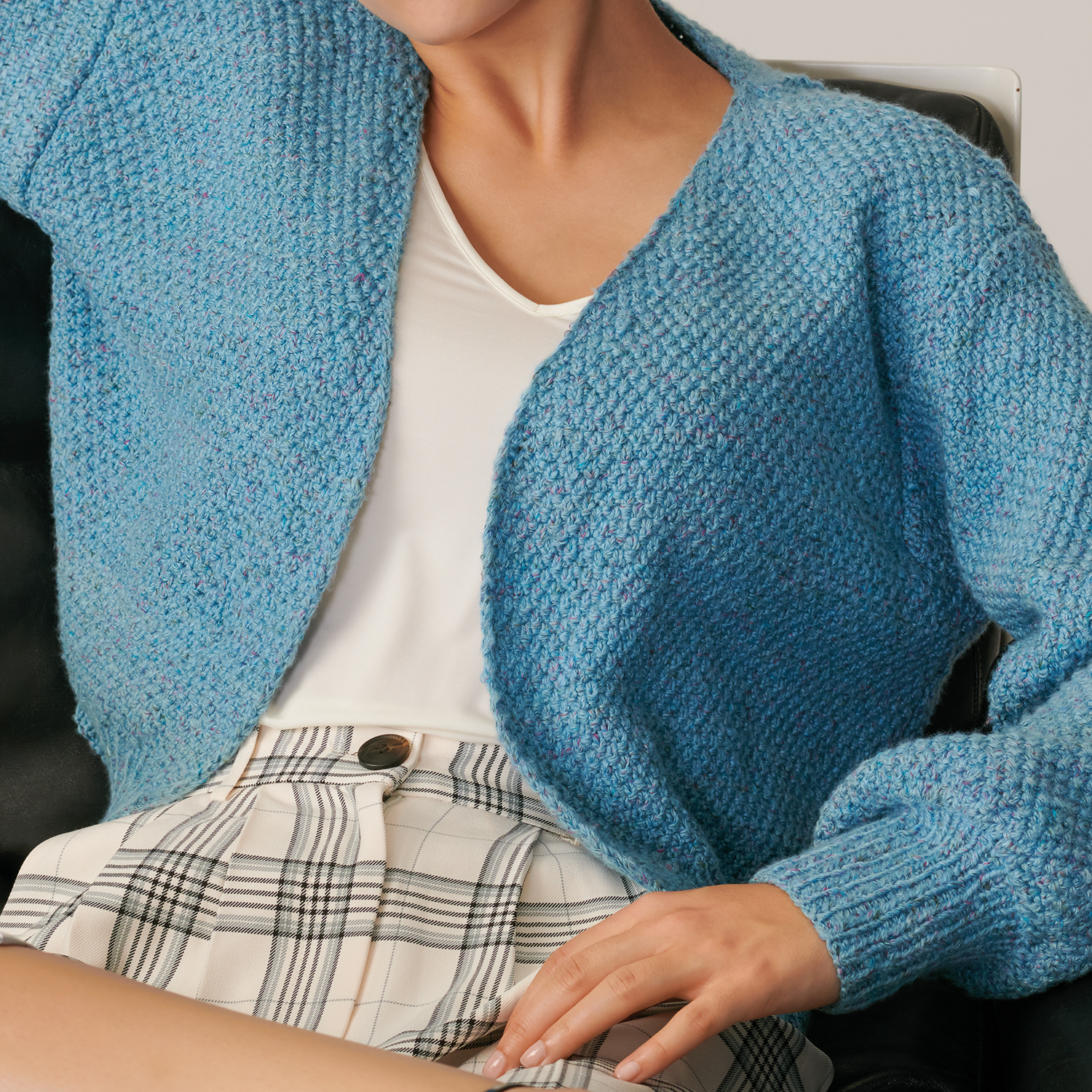 Strickanleitung Jacke aus Fashion Cottony: Blaue Strickjacke über weißem Shirt und karierter Hose.