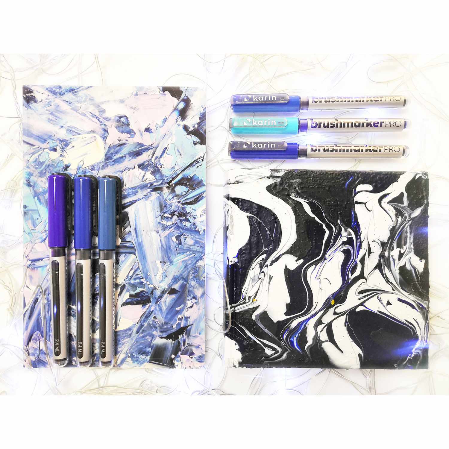 Brushmarker PRO Stifte von karin auf abstraktem Hintergrund in Blau- und Schwarztönen arrangiert.