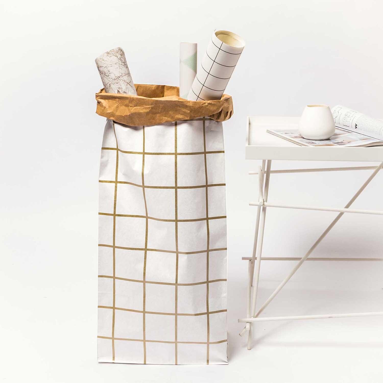 Paper Poetry Maxi-Blockbodenbeutel XL Karo in Weiß-Braun-Gold neben einem weißen Tisch. Ideal zur Aufbewahrung von Rollen und Dekoration.