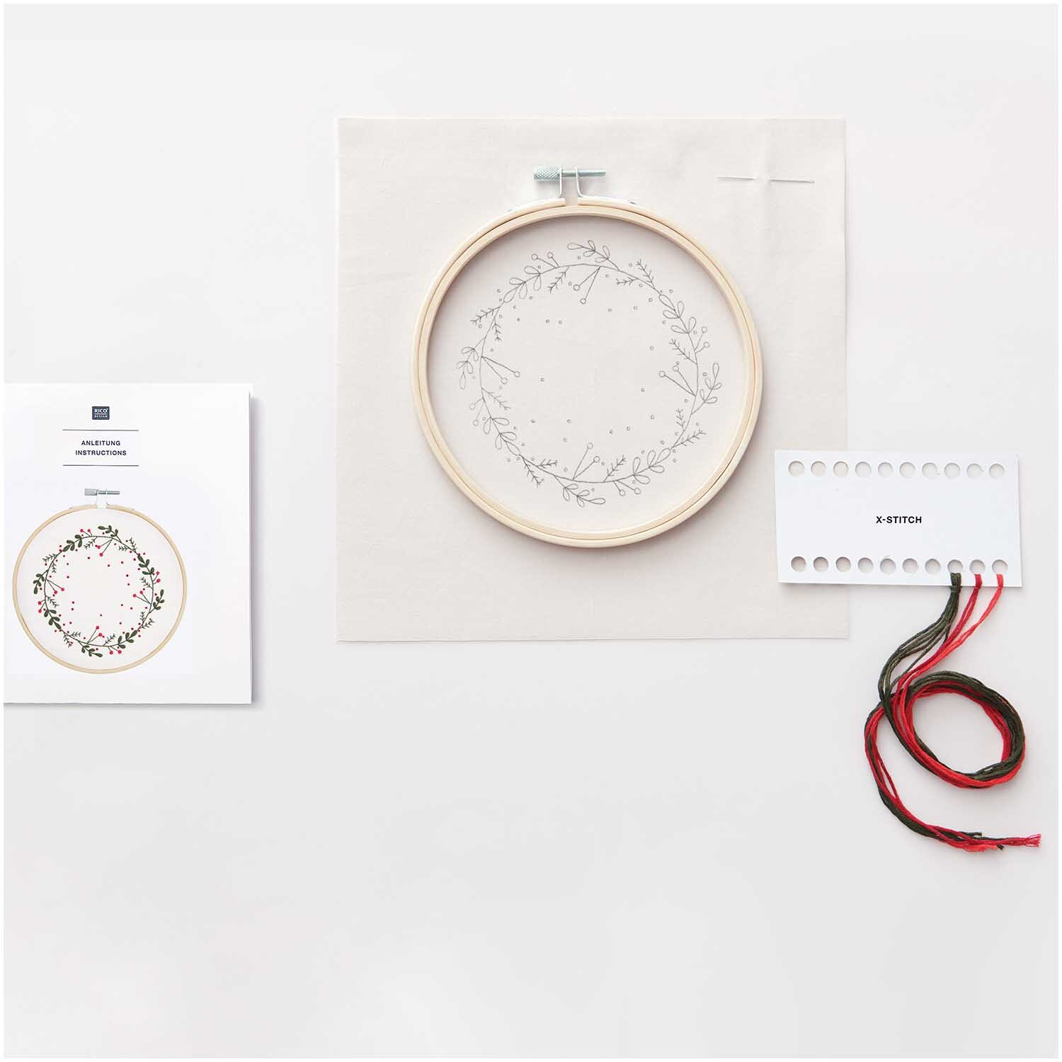 Stickpackung Kranz Bild Ø 15cm von Rico Design zeigt einen Stickrahmen mit floralem Muster, Garn und Anleitung.