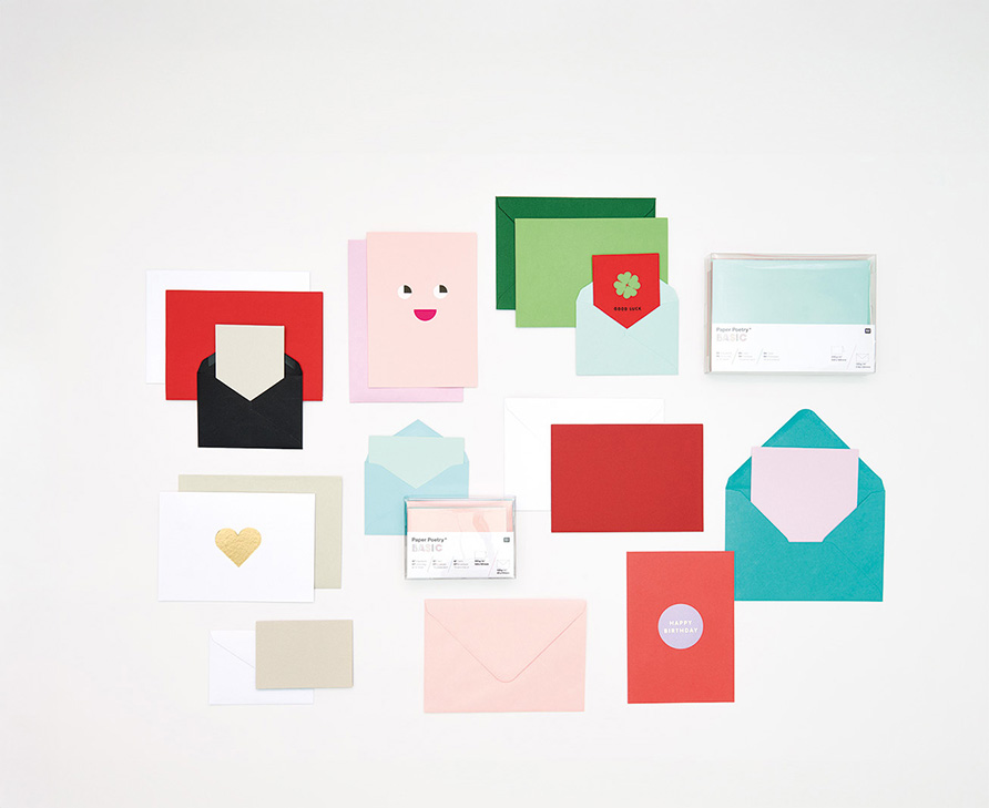 Umschläge und Karten in unterschiedlichen Farben und Größen ausgelegt und zwei verpackte Karten/Umschläge Sets. Flatlay von Produkten.