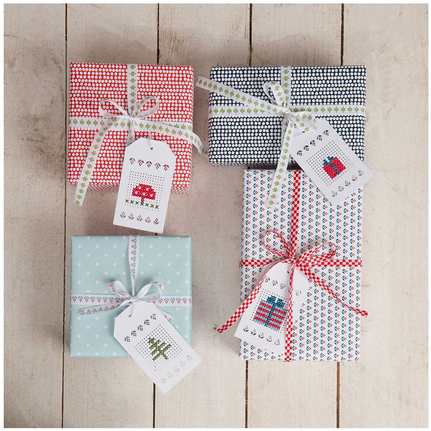 Anhänger zum Besticken creme 24 Stück von Rico Design auf Geschenken mit buntem Papier und Stickmotiven.