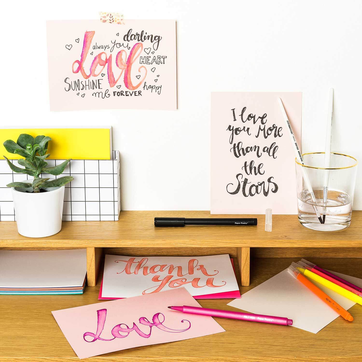 Anleitung Karten mit Handlettering gestalten: Kreative Karten mit Stiften und Pflanzen auf einem Schreibtisch arrangiert.