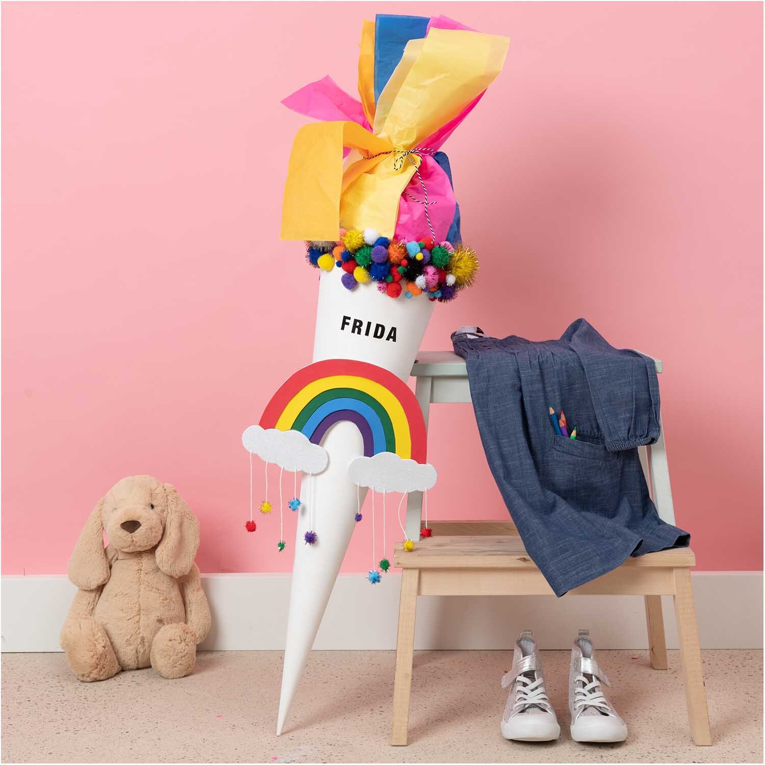 Krepp-Papier 50x250cm von Rico Design in Blau, dekoriert mit bunten Pompons und Regenbogenmotiv.