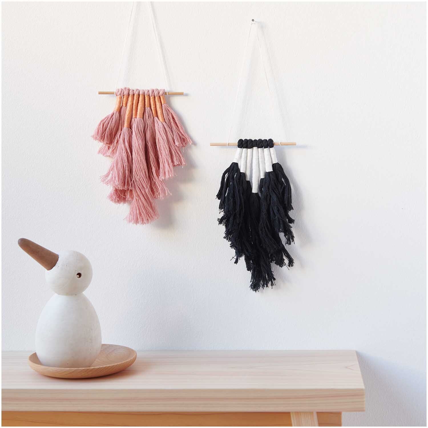 Stickgarn Set Earthy von Rico Design, 10-teilig. Zwei Wandbehänge in Rosa und Schwarz auf hellem Hintergrund.
