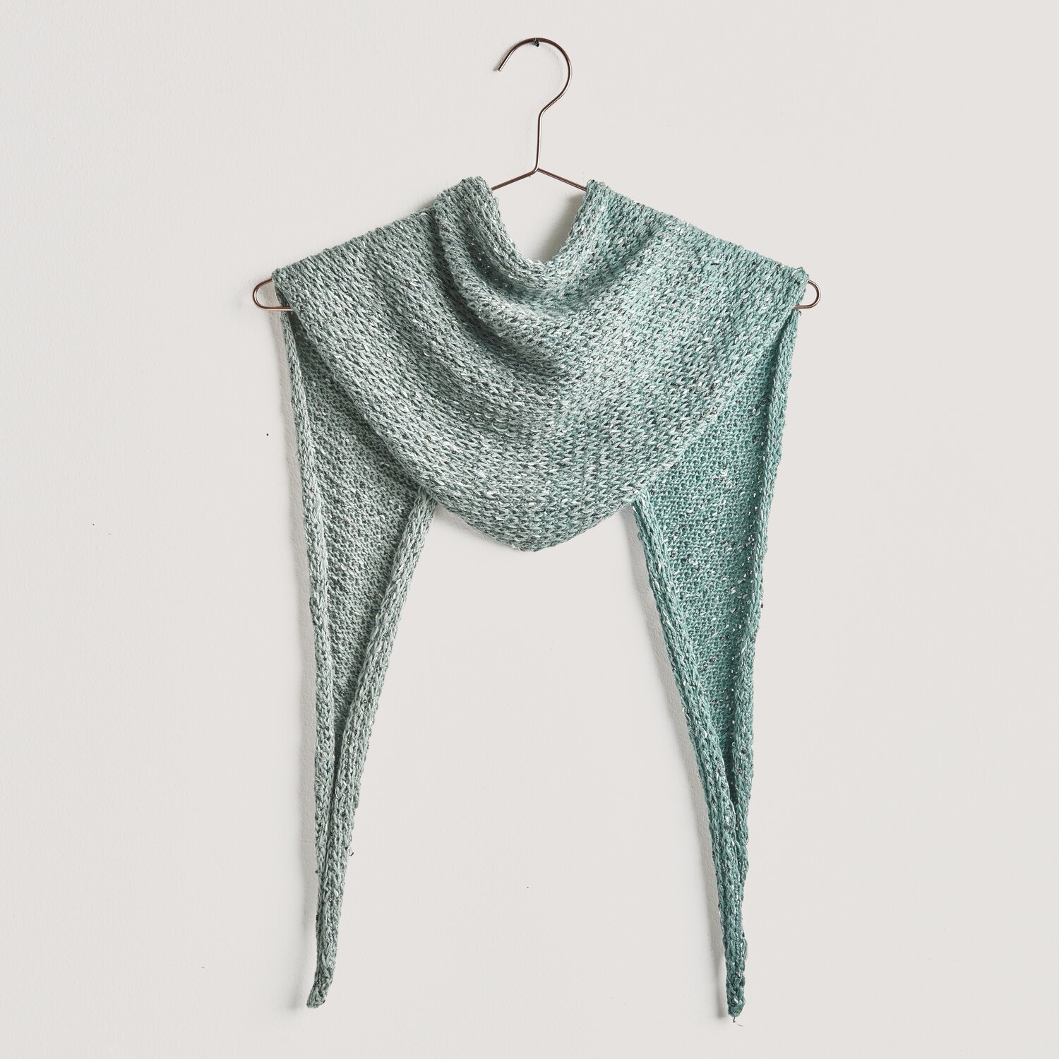 Strickset Dreieckstuch Modell 10a aus Lovewool No. 20, gehängt auf einem Kleiderbügel, in sanften Grüntönen.