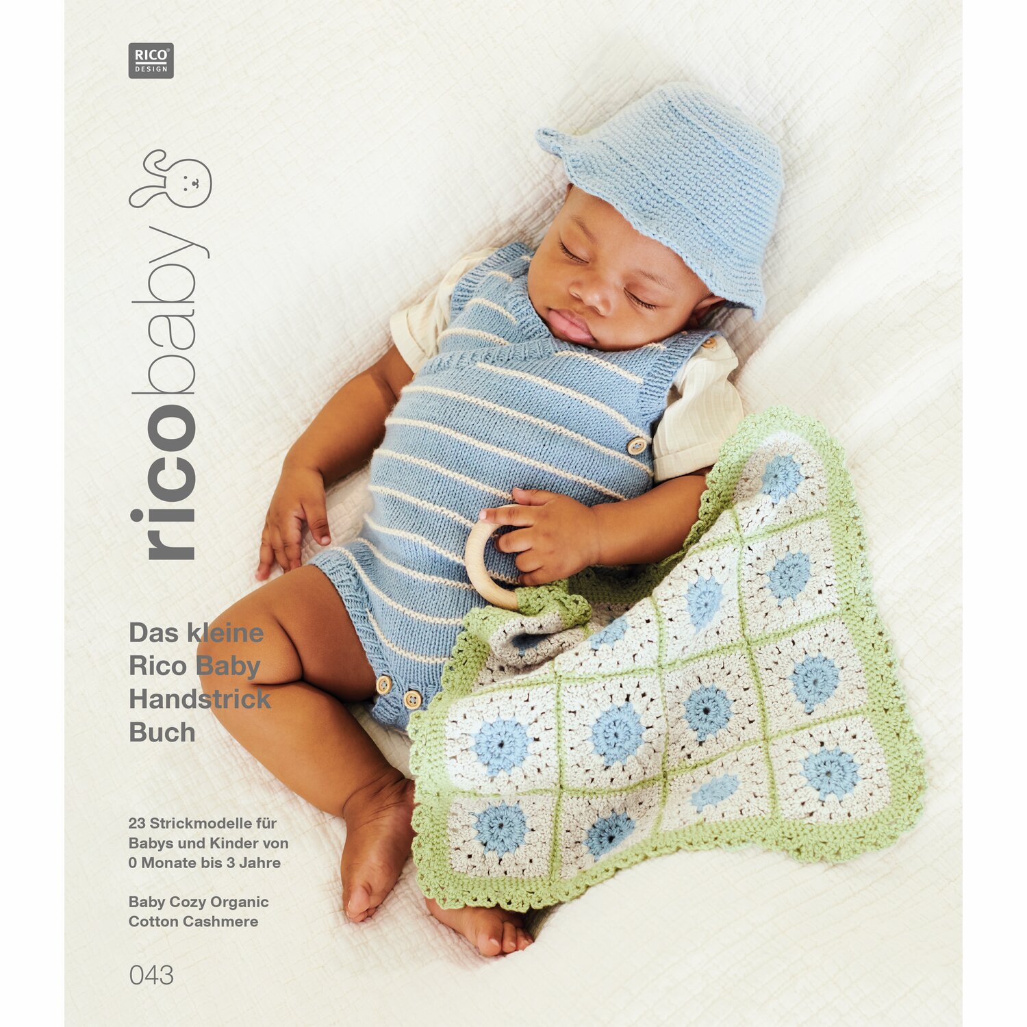 Rico Baby 043: Baby in blauem Strampler und Mütze mit gehäkelter Decke in Grün und Weiß.