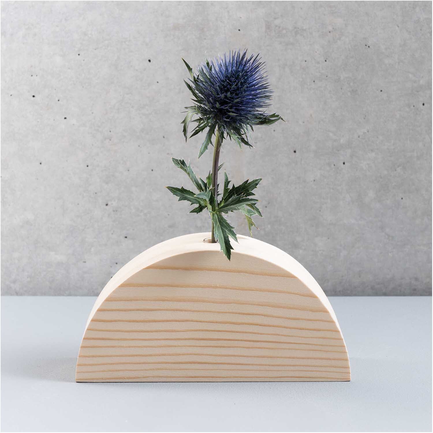 Holz-Regenbogen mit kleiner Glasvase von Rico Design, dekoriert mit einer blauen Distelblume.