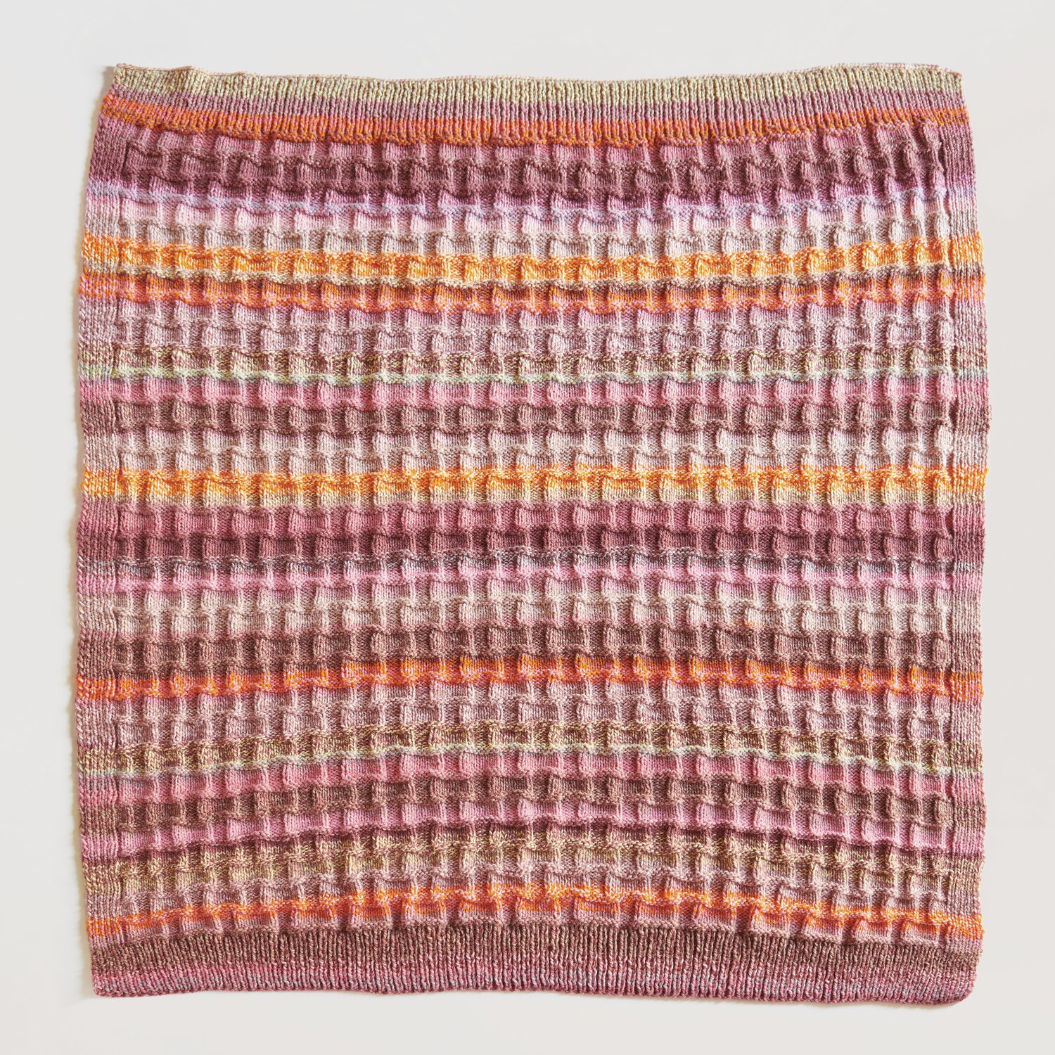 Strickset Decke Modell 13: Bunte gestrickte Decke mit Streifenmuster in Rosa, Orange und Grün.