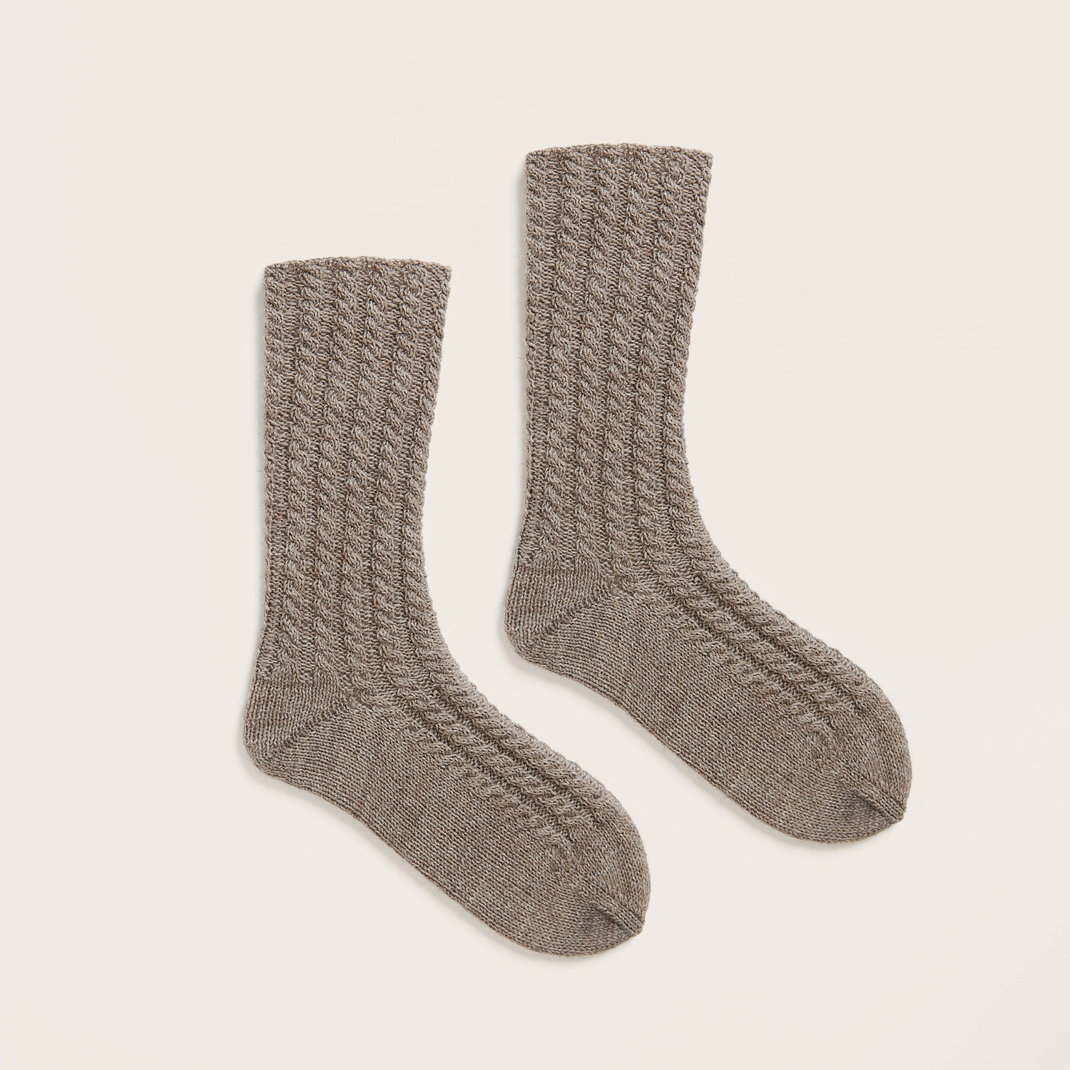 Strickset Socken Modell 02 zeigt zwei gestrickte Socken in Zopfmuster auf hellem Hintergrund.