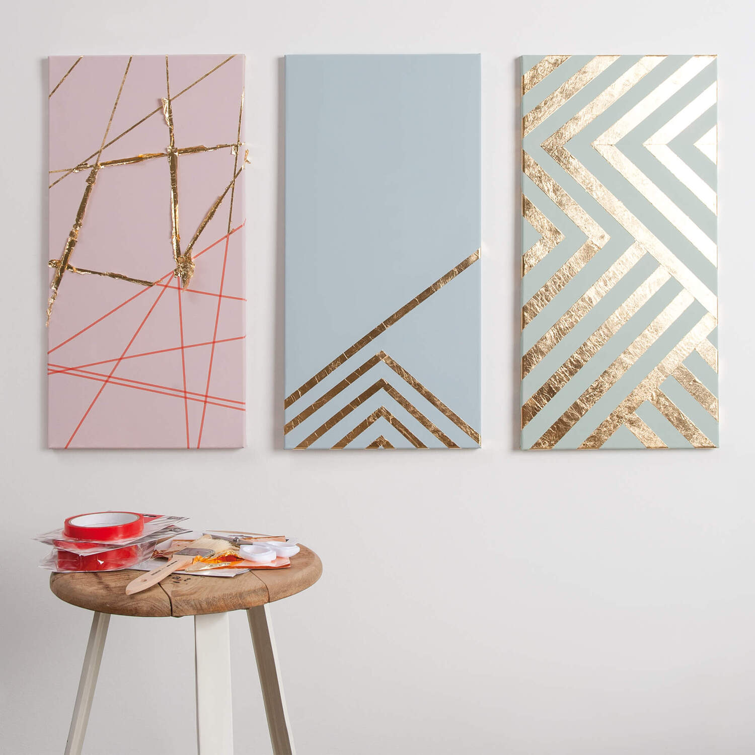 Bastelanleitung Bilder mit Blattmetall: Drei moderne Leinwände mit geometrischen Mustern und Blattmetall in Goldtönen an der Wand.