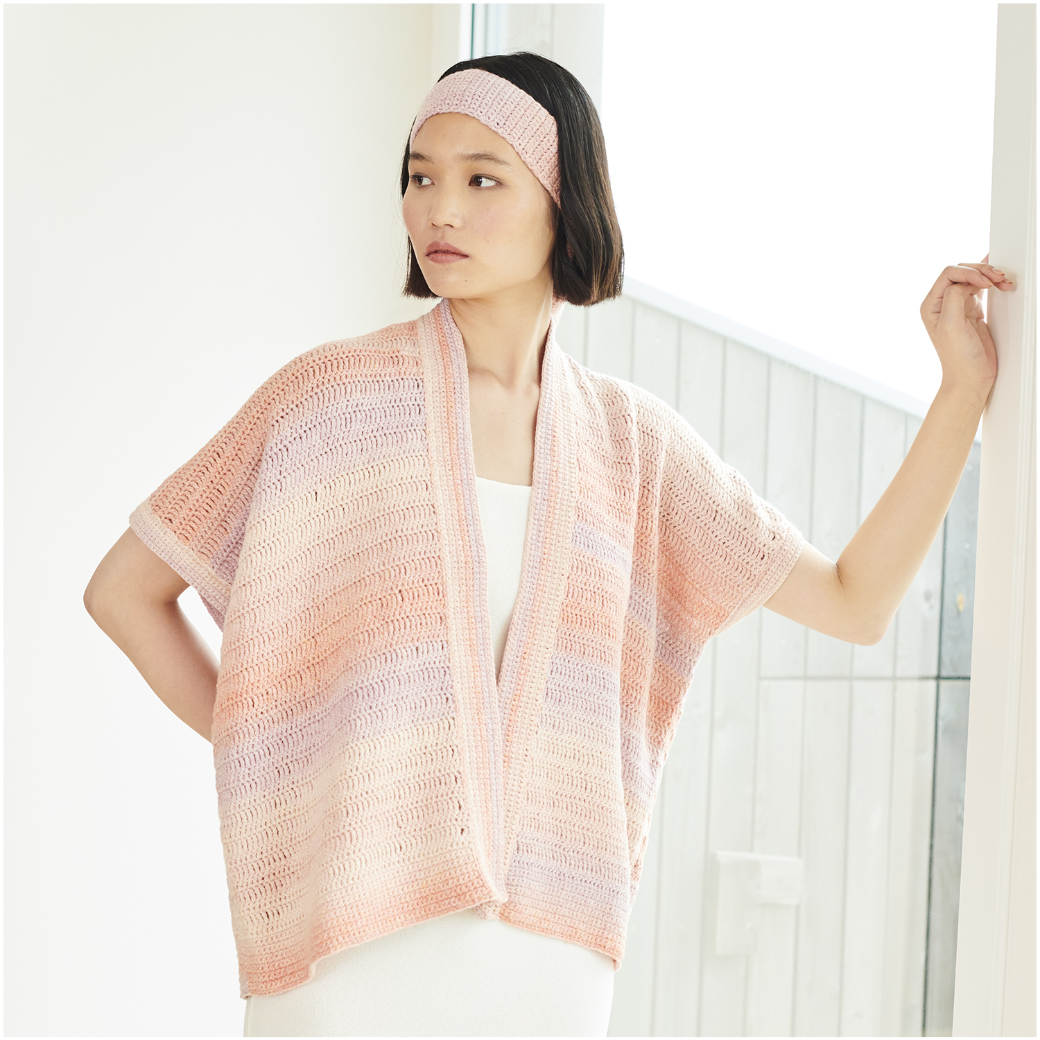 Häkelset Weste Modell 06: Frau trägt eine pastellfarbene Weste und Stirnband aus Lovewool Nr. 18.