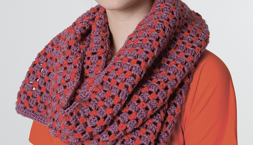 Häkelanleitung Lochmusterschal aus Soft Merino: Frau trägt lila-roten Schal mit Lochmuster.