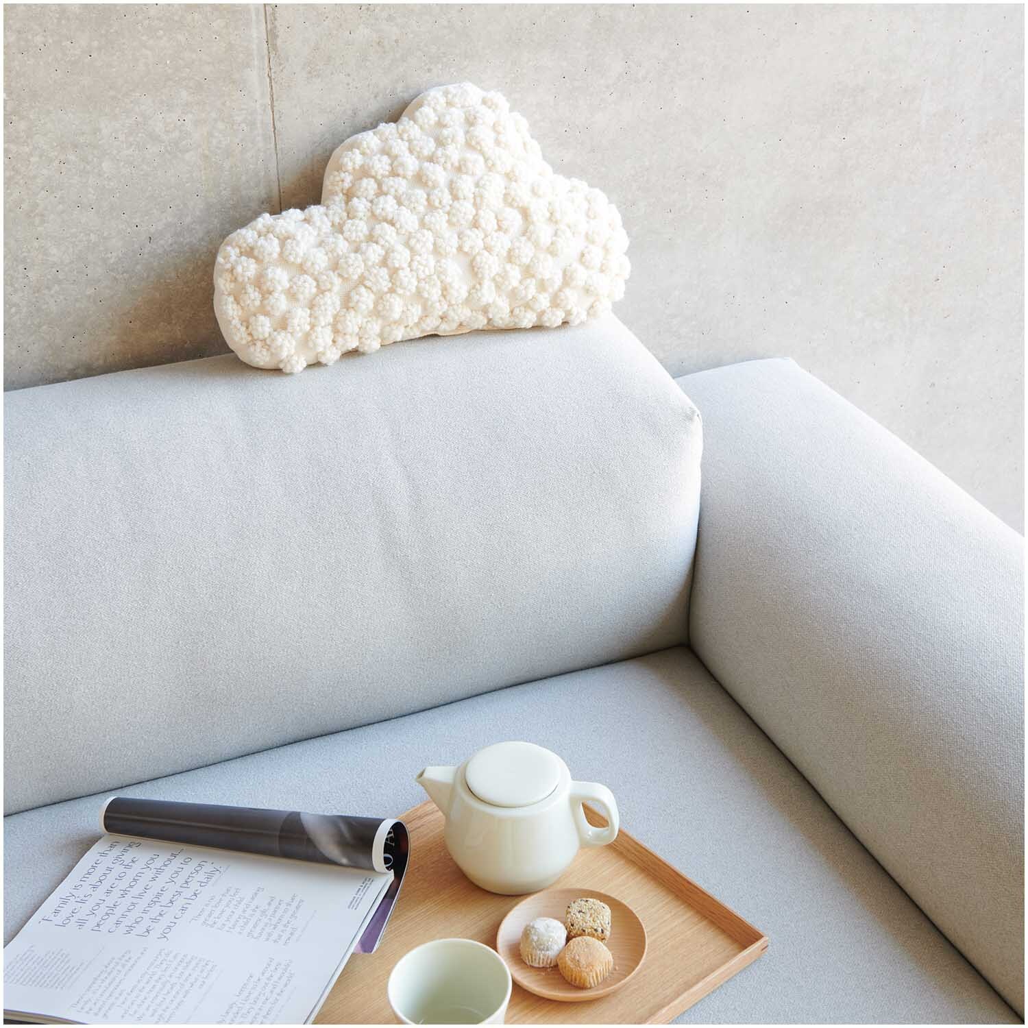 Punch Needle Packung Bild Wolke auf grauem Sofa, dekoriert mit Teeservice und Buch, von Rico Design.