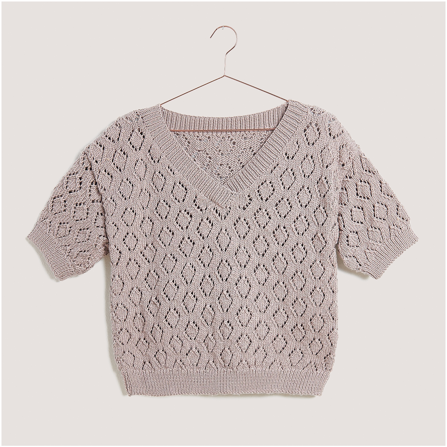 Strickset Shirt Modell 10 aus Lovewool Nr. 18, gestrickt in einem eleganten Lochmuster, hängend auf einem Kleiderbügel.