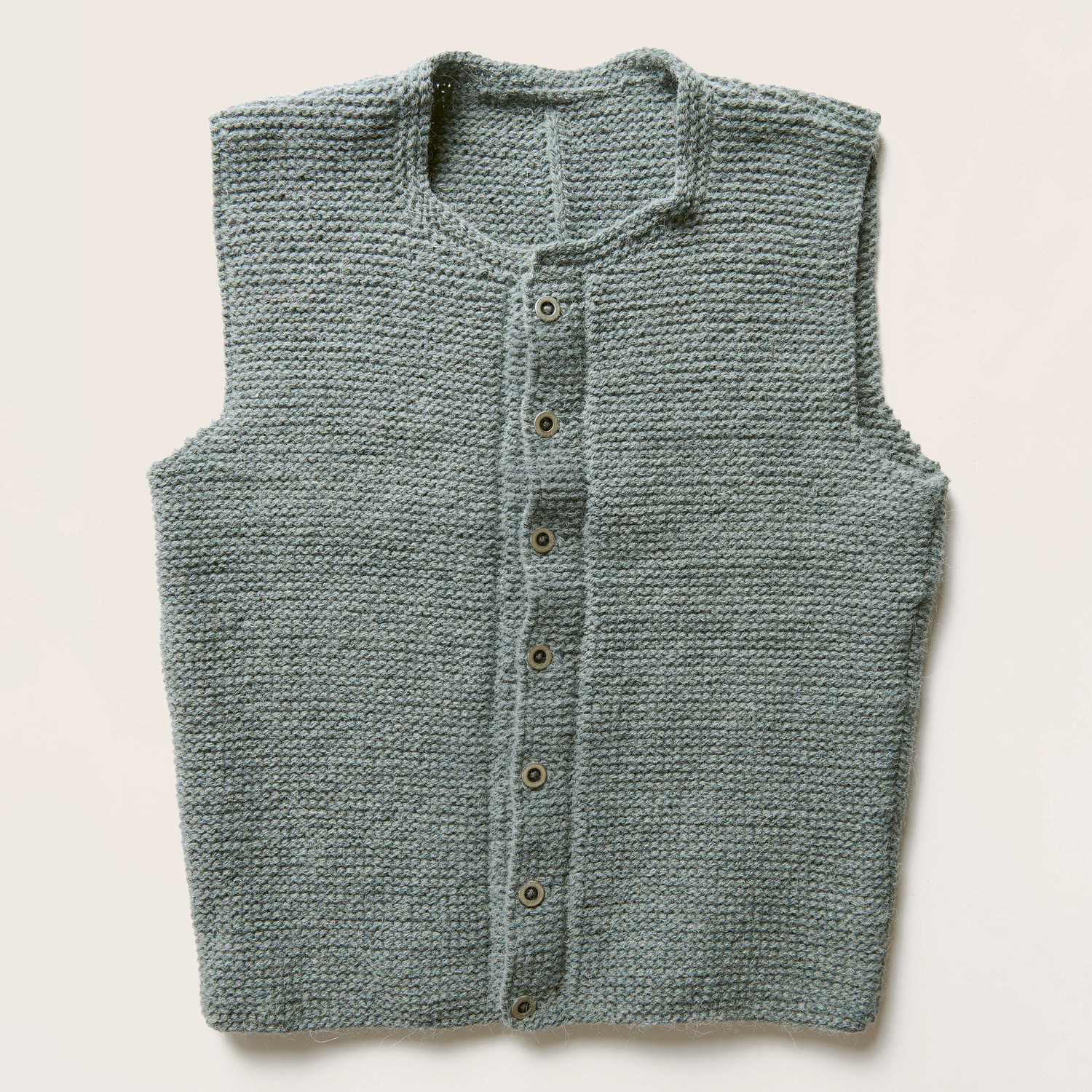 Strickset Herrenweste Modell 18 aus Trachtenbuch I mog di zeigt eine blaue Weste mit flachen Trachtenknöpfen, ideal für traditionelle Anlässe. Von Rico Design.
