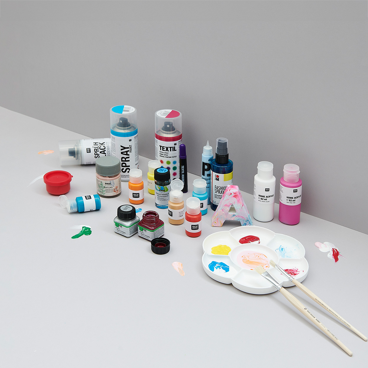 Acrylfarben, Bastelfarben, Lacke und Pinsel in verschiedenen Farben. Fotosetting graue Ecke.