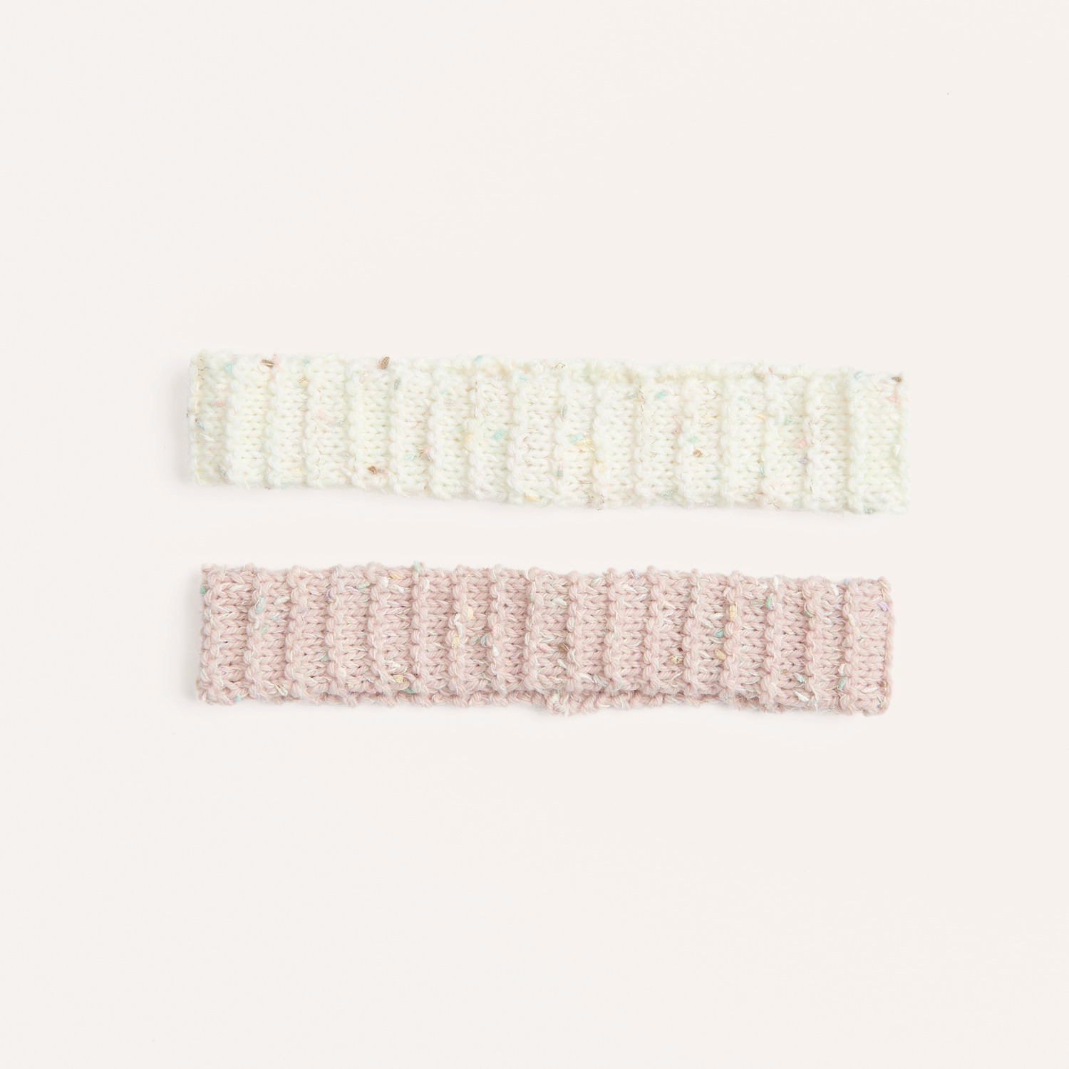 Strickset Stirnband Modell 05 zeigt zwei gestrickte Stirnbänder in Creme und Rosa auf hellem Hintergrund.