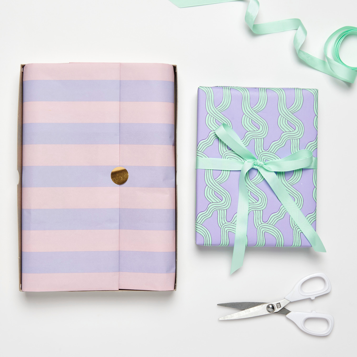 Seidenpapier Streifen Rosa-Flieder, dekorativ verpackt, neben Geschenkpapier und Schere arrangiert.
