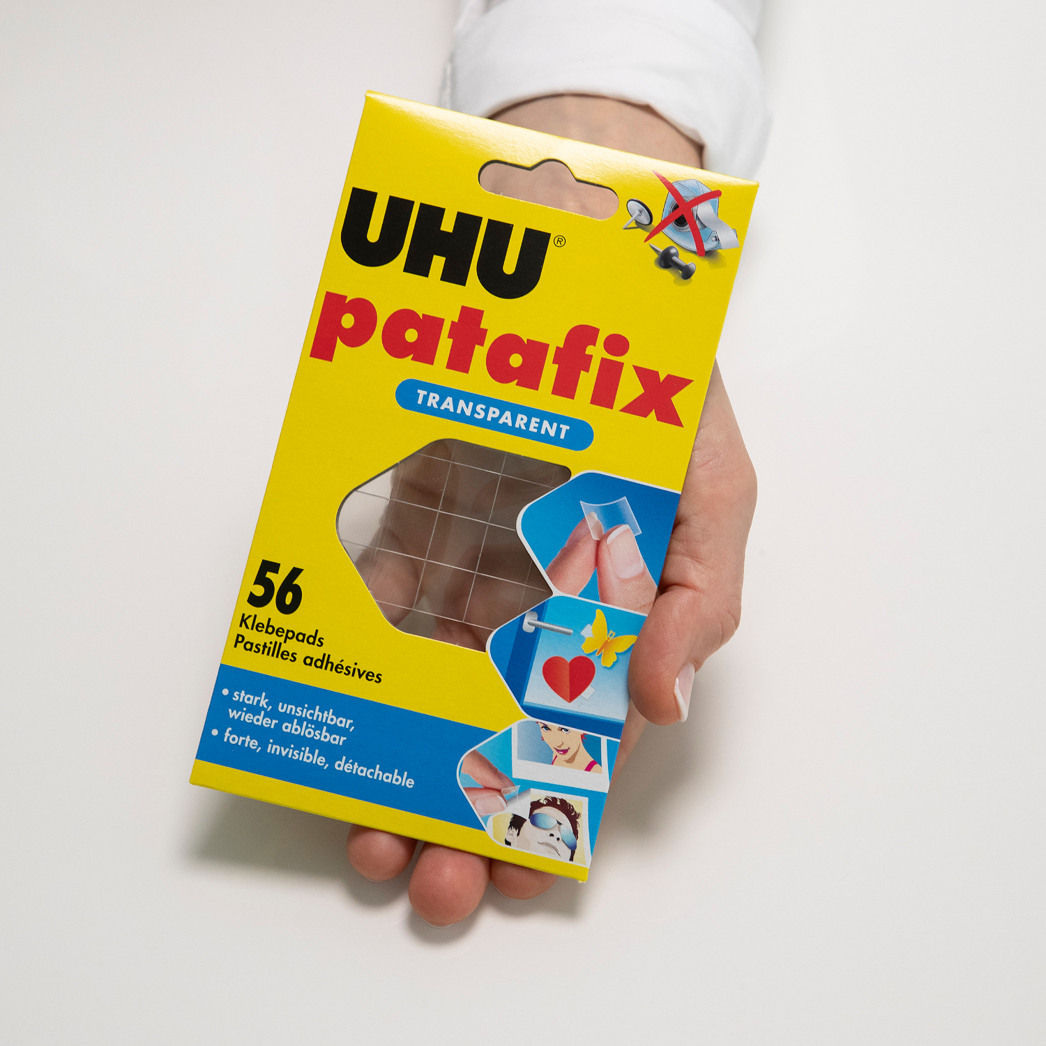 patafix transparent 56 Klebepads von UHU in gelber Verpackung, gehalten von einer Hand. Ideal für unsichtbares Befestigen.