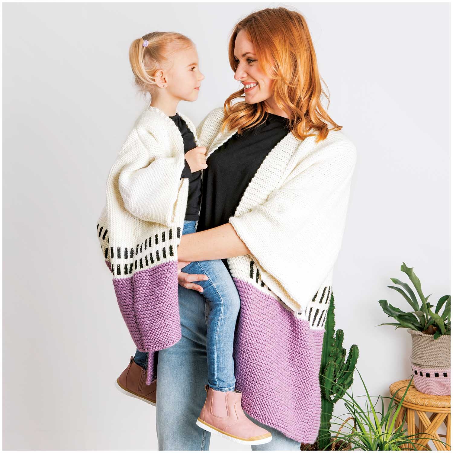 Essentials Mega Wool chunky: Mutter und Tochter in gestrickten Cardigans in Weiß und Lila.