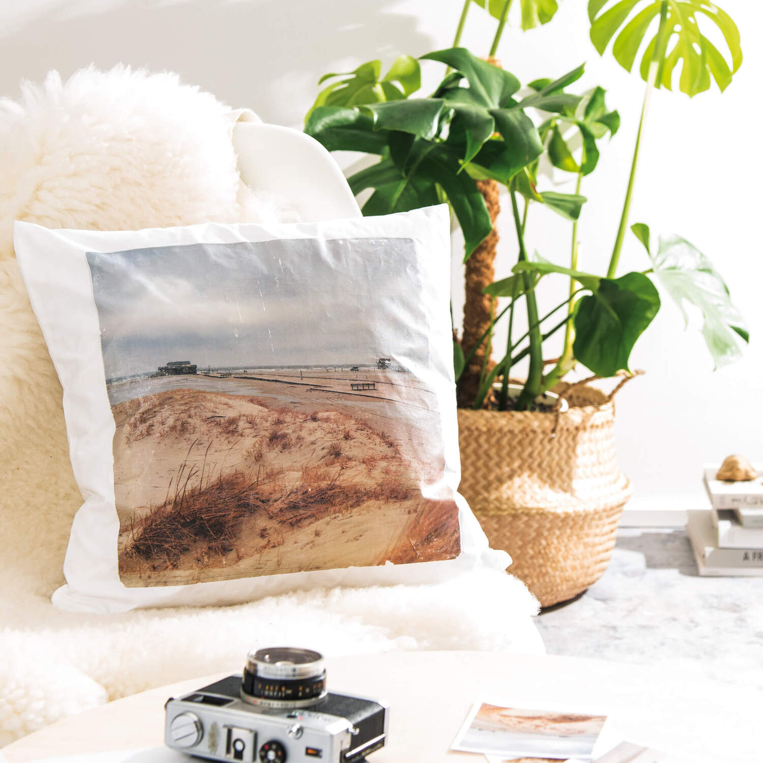 Bastelanleitung Fototransfer auf Stoff: Kissen mit Strandmotiv, umgeben von Pflanzen und Kamera.