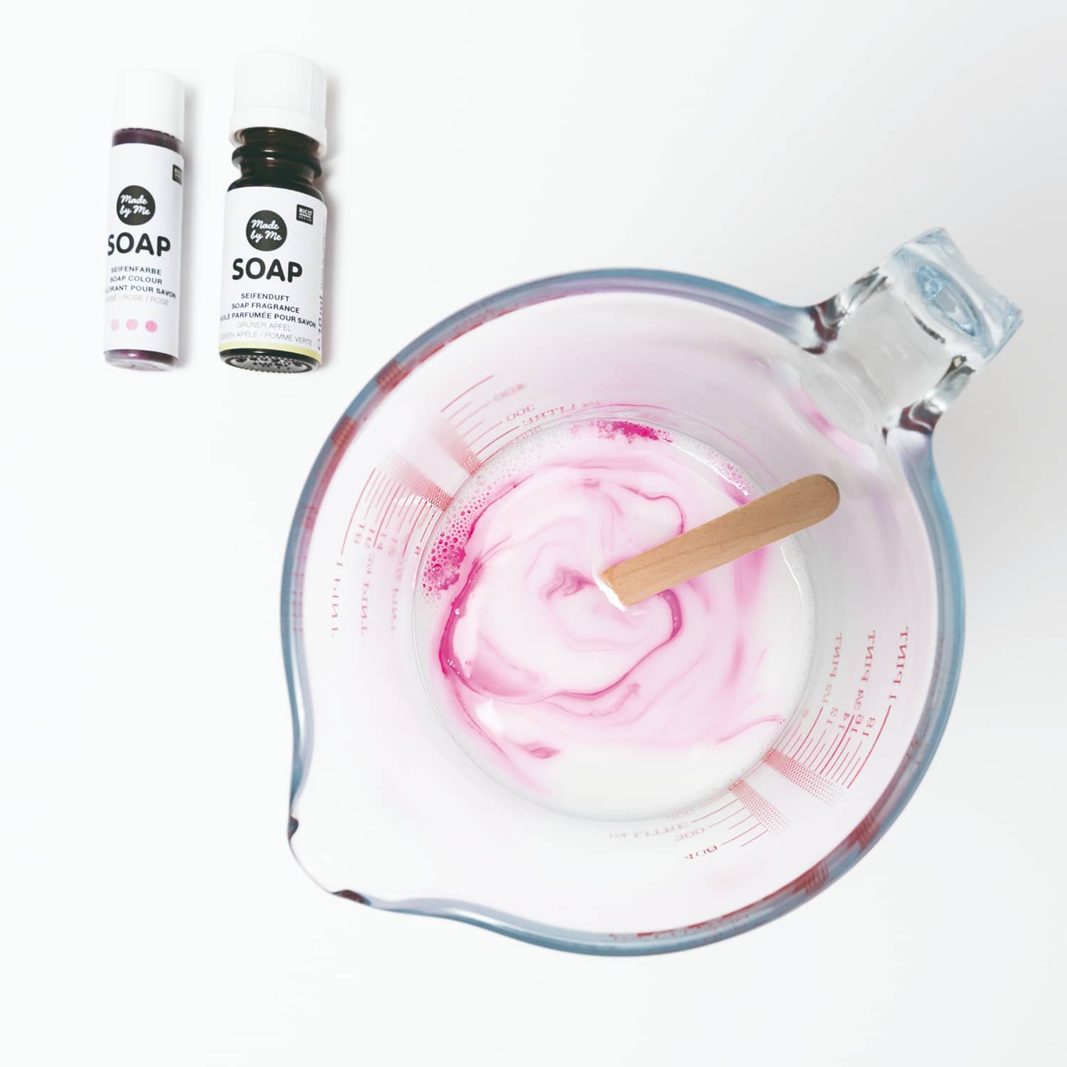Ein Messbecher mit geschmolzener Seifenmasse wird mit rosa Farbe angereichert